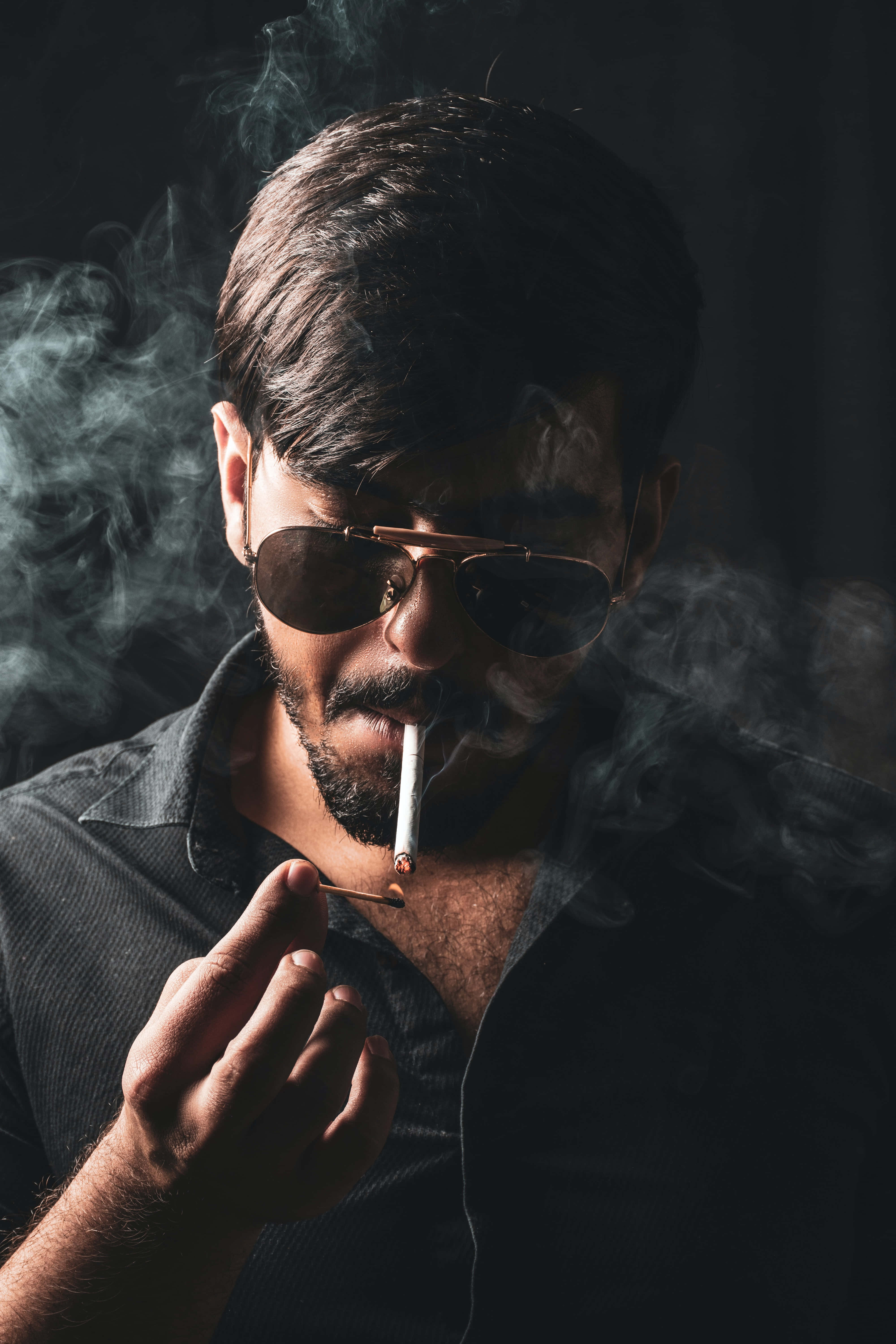 Man 桌布 壁紙 — 一個留鬍鬚的男人戴著飛行員太陽眼鏡，在黑暗背景中抽煙，煙霧繚繞。