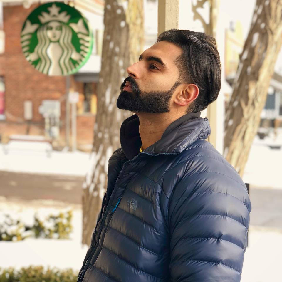 穿著藍色羽絨外套的男人在雪景城市場景中於Starbucks附近向上看。