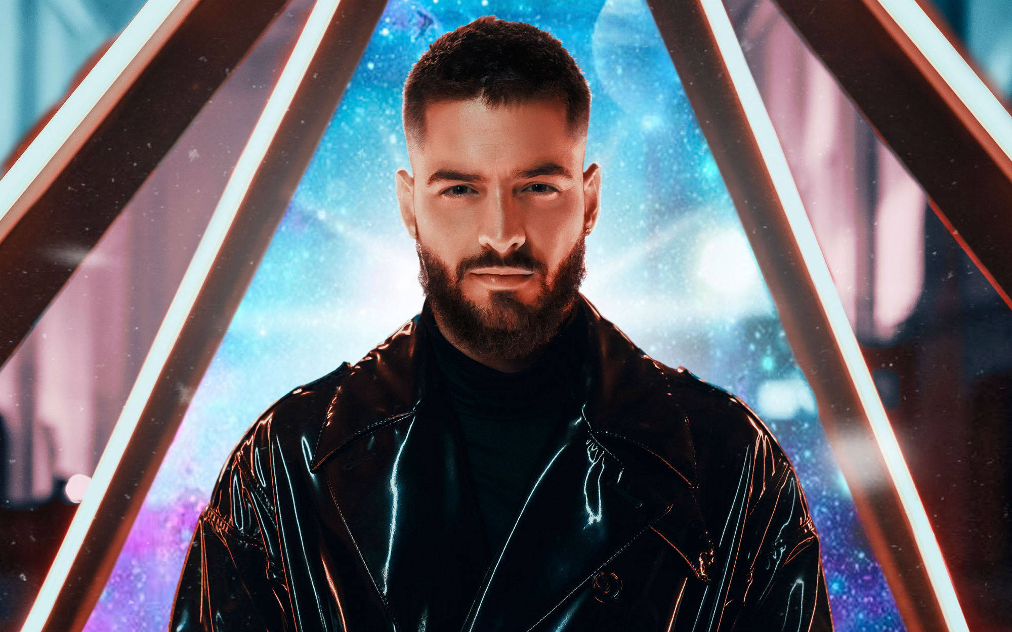 Maluma 桌布 壁紙 — 一個留鬍鬚的男人穿著閃亮的黑色外套，自信地站在發光霓虹三角形框內，背景是宇宙星空。