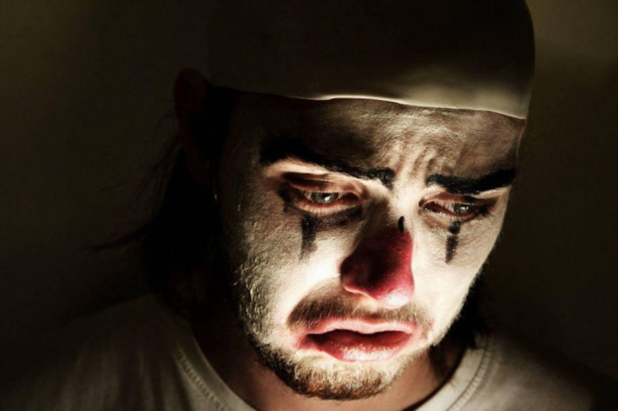 Crying 桌布 壁紙 — 一個痛苦小丑的特寫，妝容被淚水弄花，紅鼻子在戲劇性燈光下。