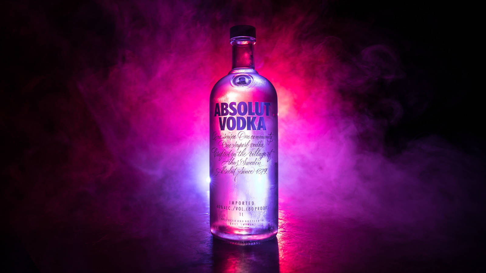 Vodka 桌布 壁紙 — 一個發光的 Absolut Vodka 酒瓶在黑暗背景下，立於鮮豔的粉紅和紫色煙霧中央。