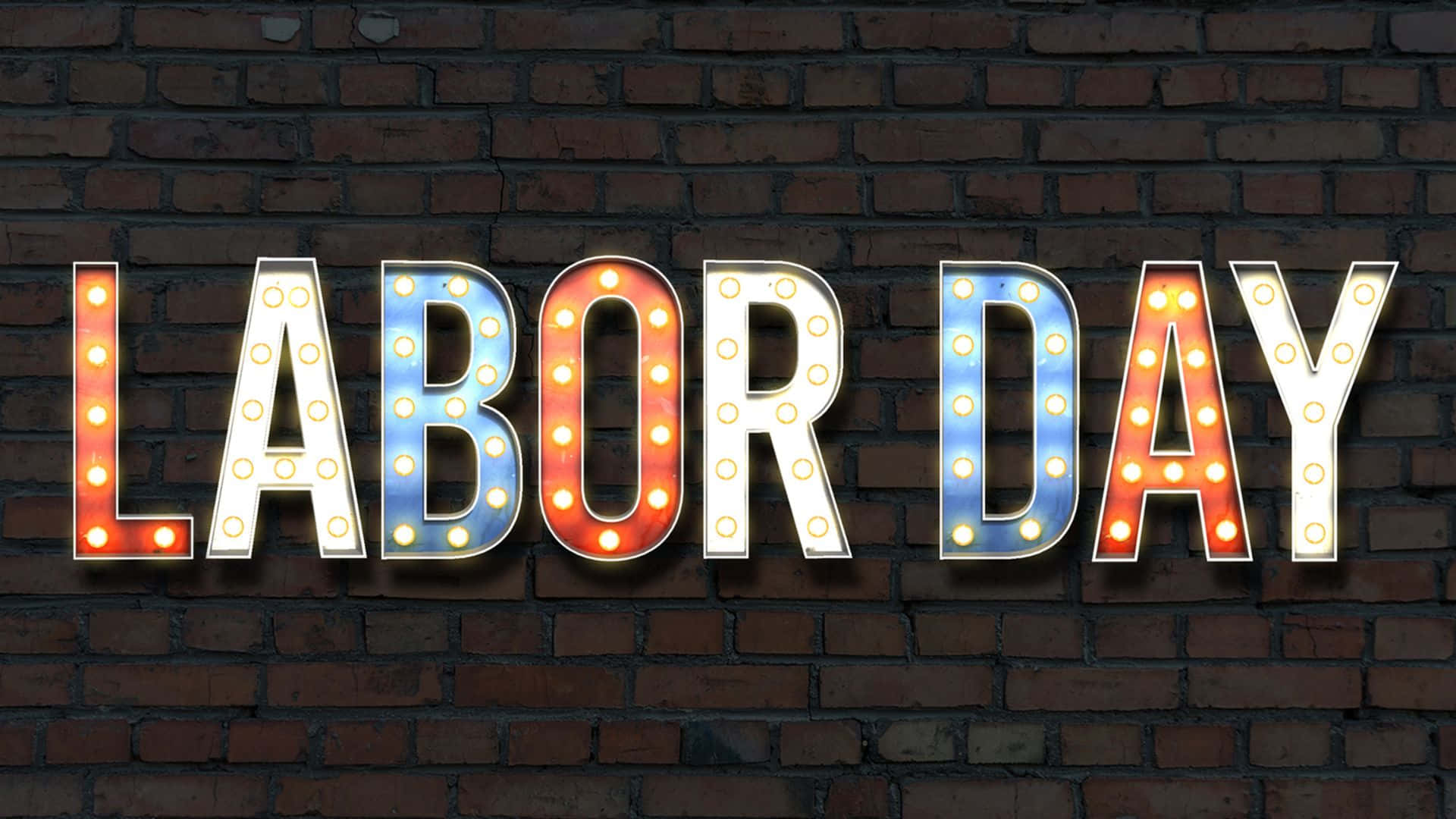 勞動節 桌布 壁紙 — 一個發光的「LABOR DAY」招牌，帶有暖色和冷色燈光，安裝在深色磚牆上。