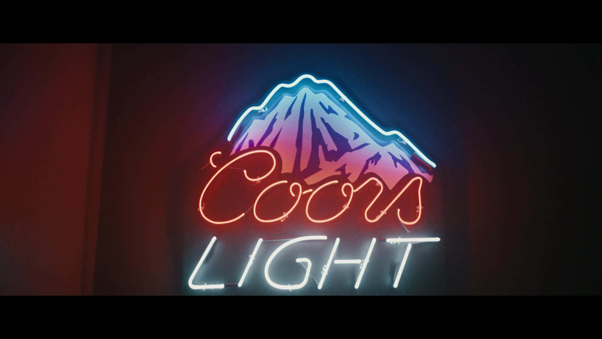 Coors Light 桌布 壁紙 — 一個發光的Coors Light霓虹燈牌，在深色牆壁上呈現藍色和粉紅色的山脈輪廓。