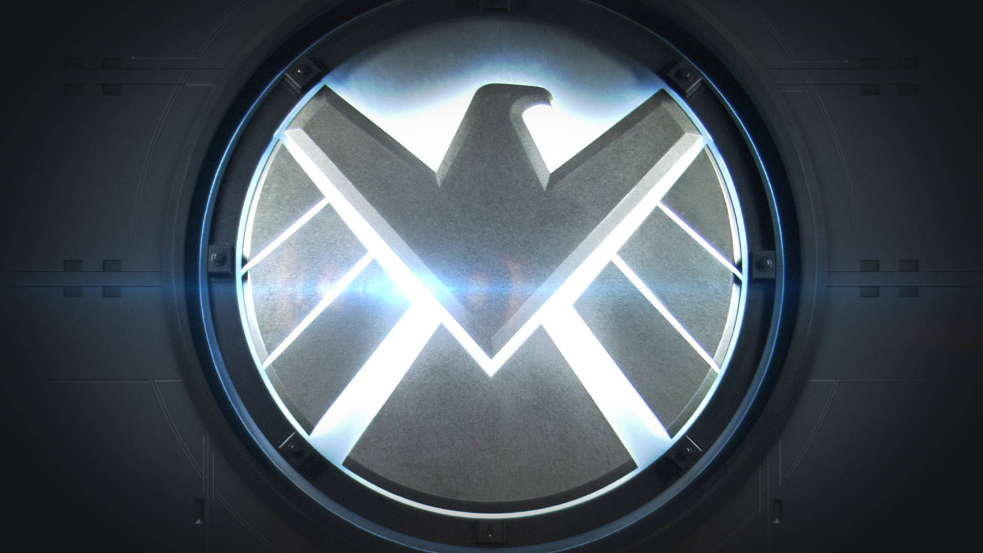 漫威 桌布 壁紙 — 一個發光的S.H.I.E.L.D.標誌透過黑暗高科技房間內的圓形金屬觀察窗明亮地閃耀。