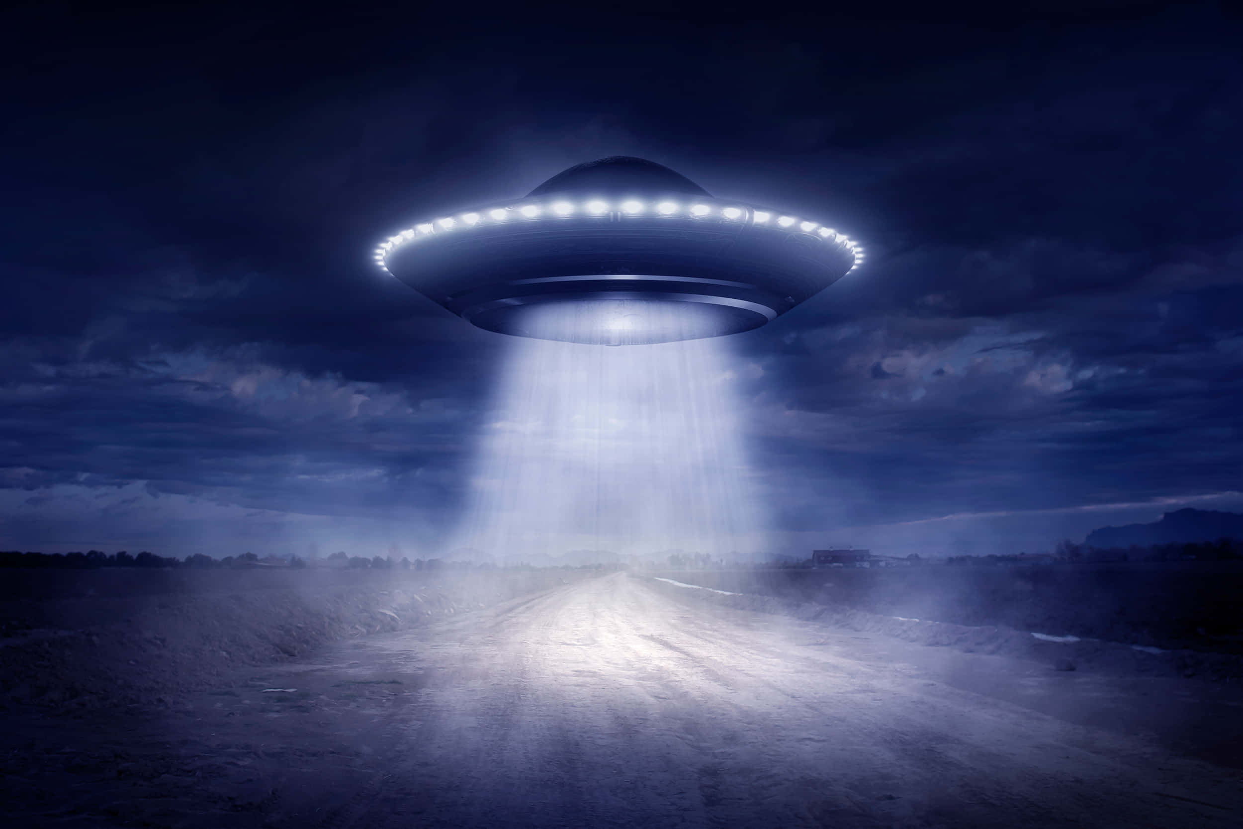 幽浮 桌布 壁紙 — 一個發光的UFO在夜晚盤旋在一條荒蕪的道路上空，將明亮的光束投射到塵土飛揚的小路上。