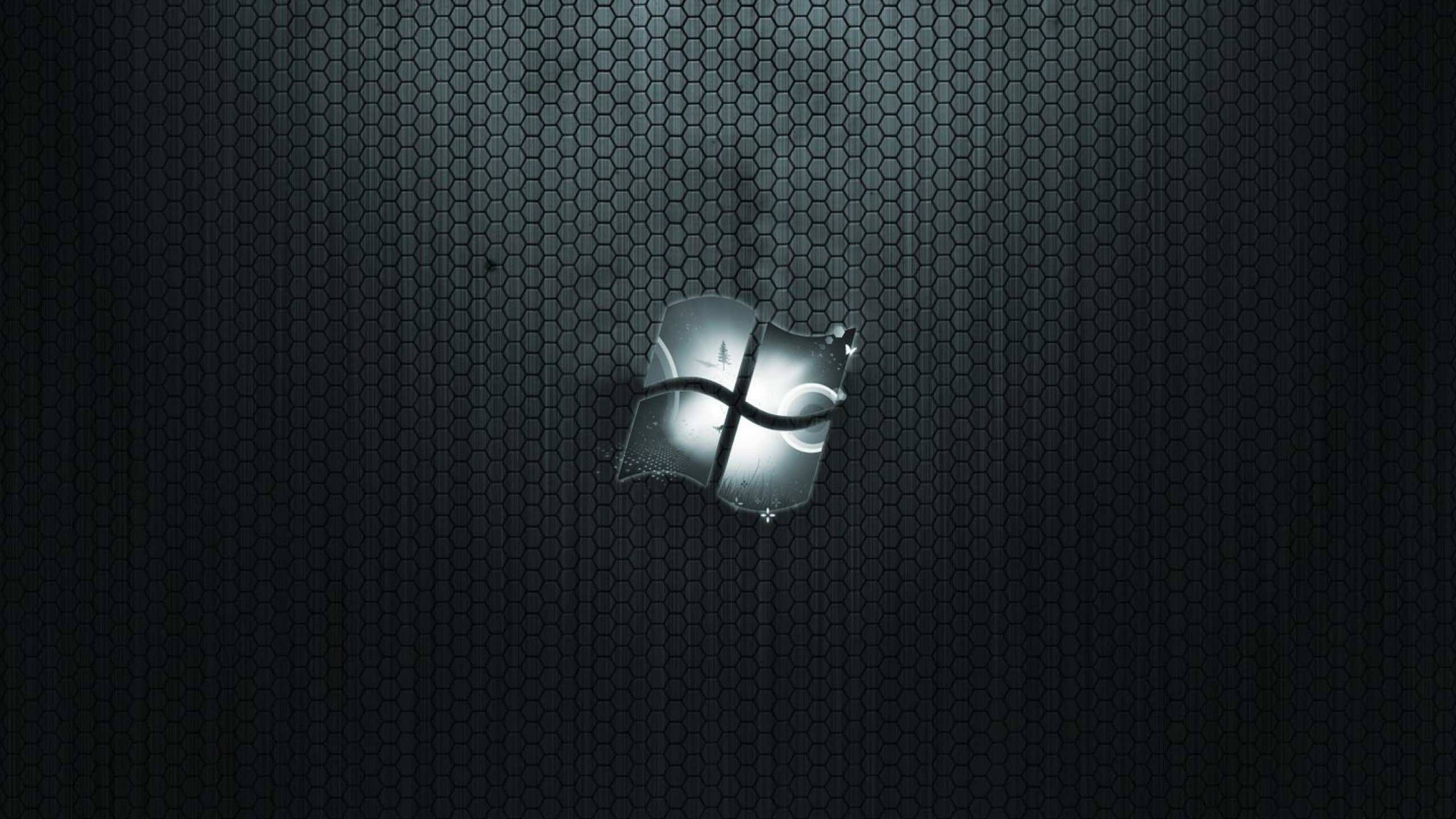 MacBook 動態圖片 桌布 壁紙 — 一個發光的Windows標誌，置於深色六角網格背景中央，帶有微妙的光線。