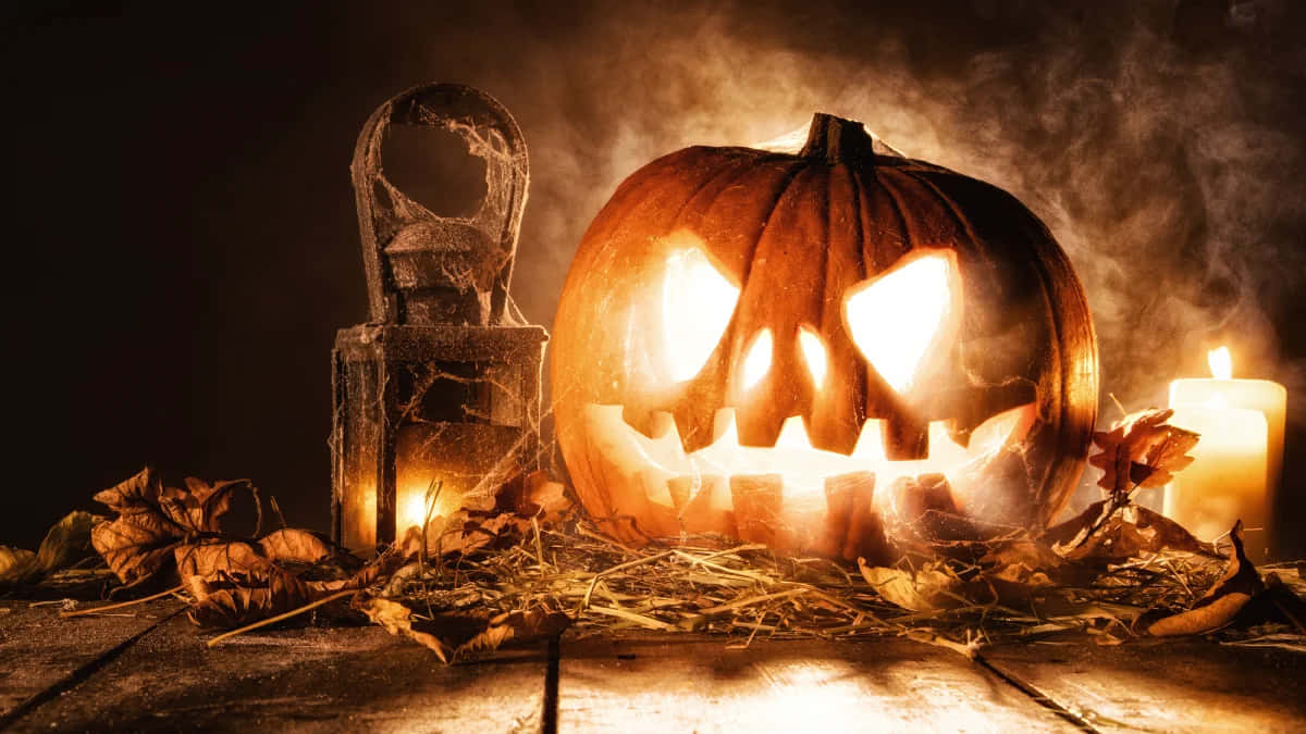 Creepy Halloween 桌布 壁紙 — 一個發光的傑克南瓜燈，帶有鋒利的牙齒，坐在乾草上，周圍是乾燥的樹葉和蠟燭，在煙霧瀰漫的黑暗中。