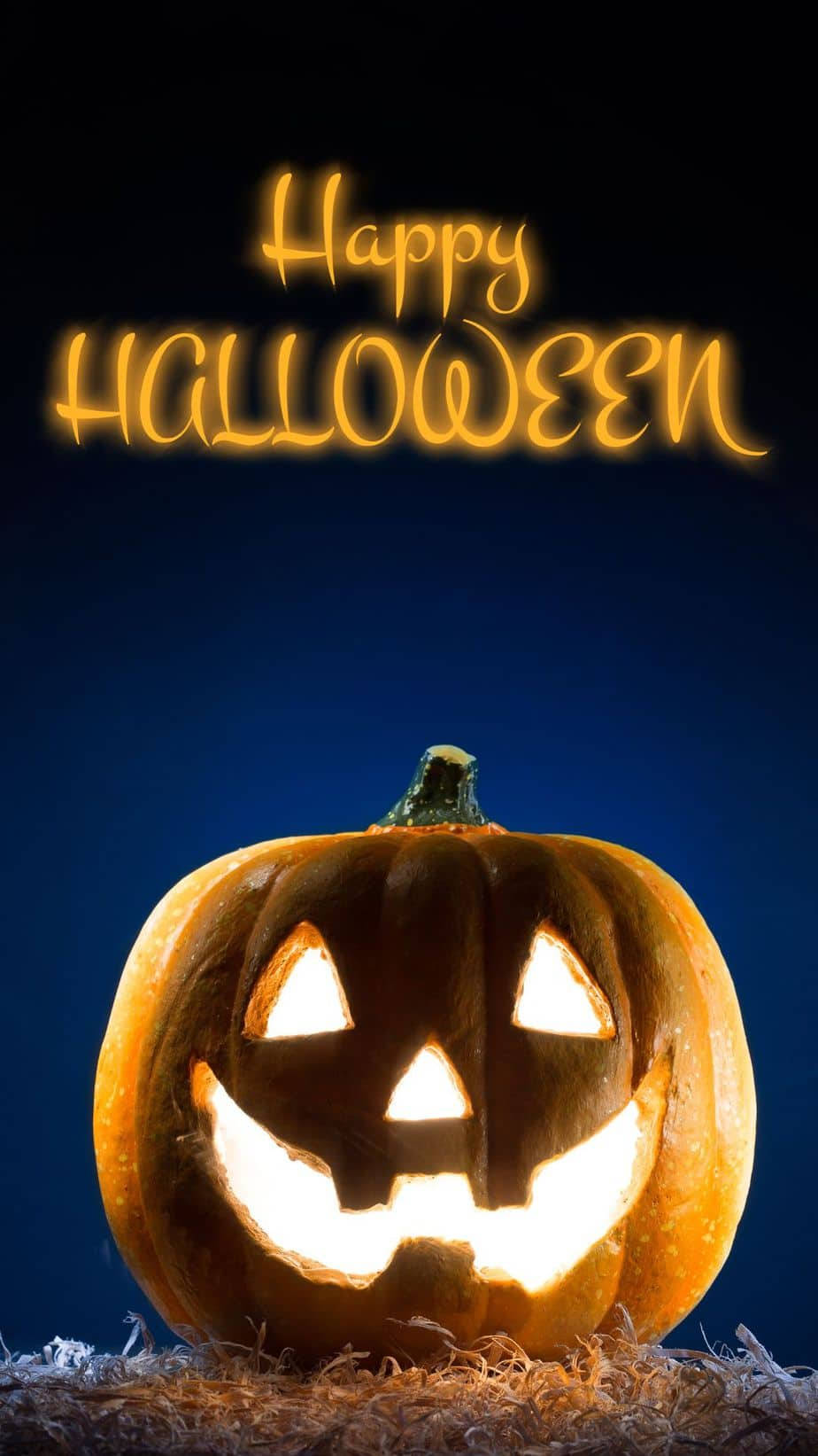 Spooky Season 桌布 壁紙 — 一個發光的傑克南瓜燈，帶有雕刻的微笑，坐在乾草上，背景是深藍色的夜空，上方有「Happy Halloween」文字。