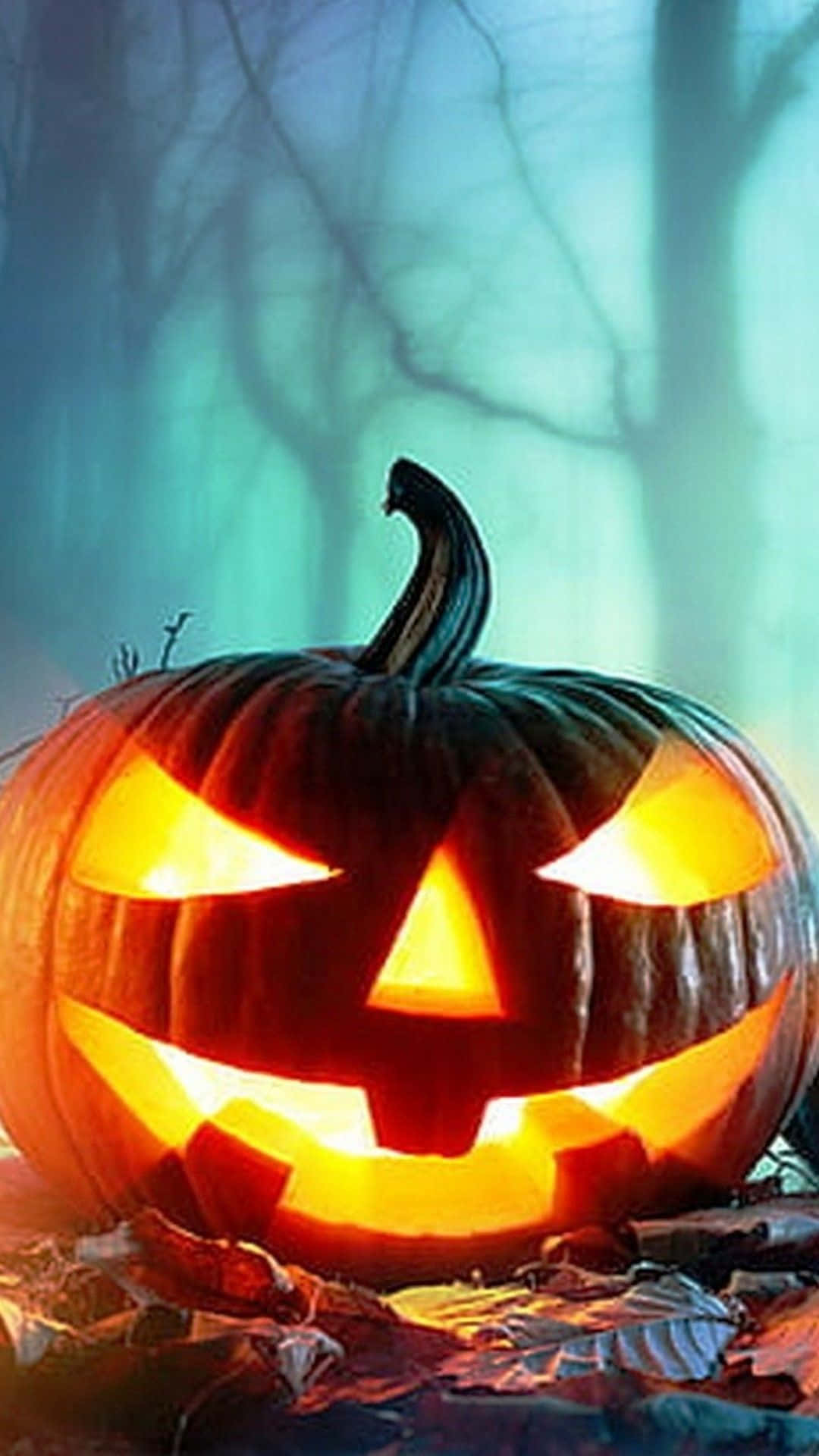 Halloween Pumpkin 桌布 壁紙 — 一個發光的傑克南瓜燈，帶著兇惡的笑容，坐在暮色中霧氣瀰漫、陰森恐怖的森林裡的落葉中。