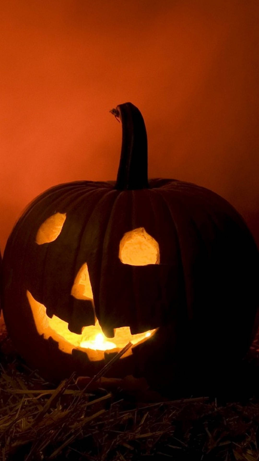 Pumpkin 桌布 壁紙 — 一個發光的傑克南瓜燈，有著寬闊的笑容和三角形眼睛，坐在乾草上，背景是溫暖的橙色。