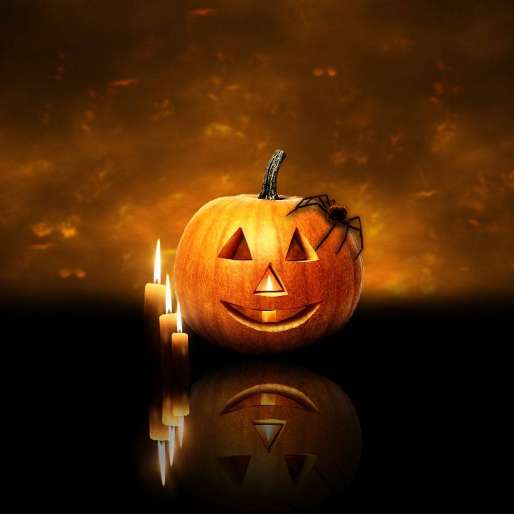 Halloween iPad 桌布 壁紙 — 一個發光的傑克南瓜燈，莖上有一隻蜘蛛，旁邊有閃爍的蠟燭，背景是溫暖的橙色。