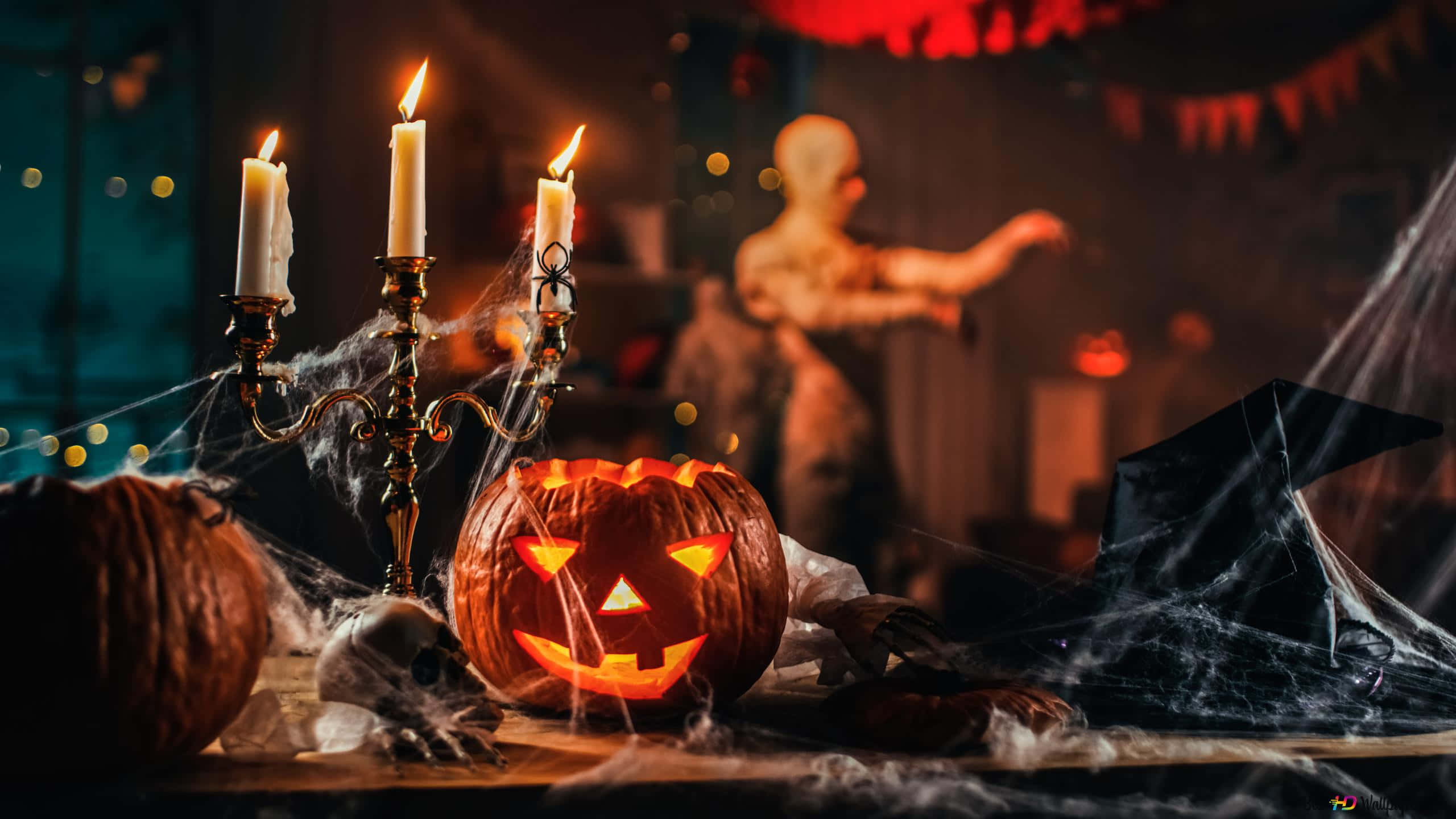 Halloween Candles 桌布 壁紙 — 一個發光的傑克南瓜燈放在蠟燭和蜘蛛網旁邊，背景有一個模糊的殭屍。