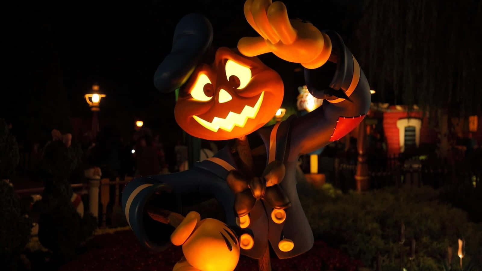 3d Halloween 桌布 壁紙 — 一個發光的傑克南瓜燈米奇老鼠公仔在萬聖節主題公園夜間愉快地揮手。