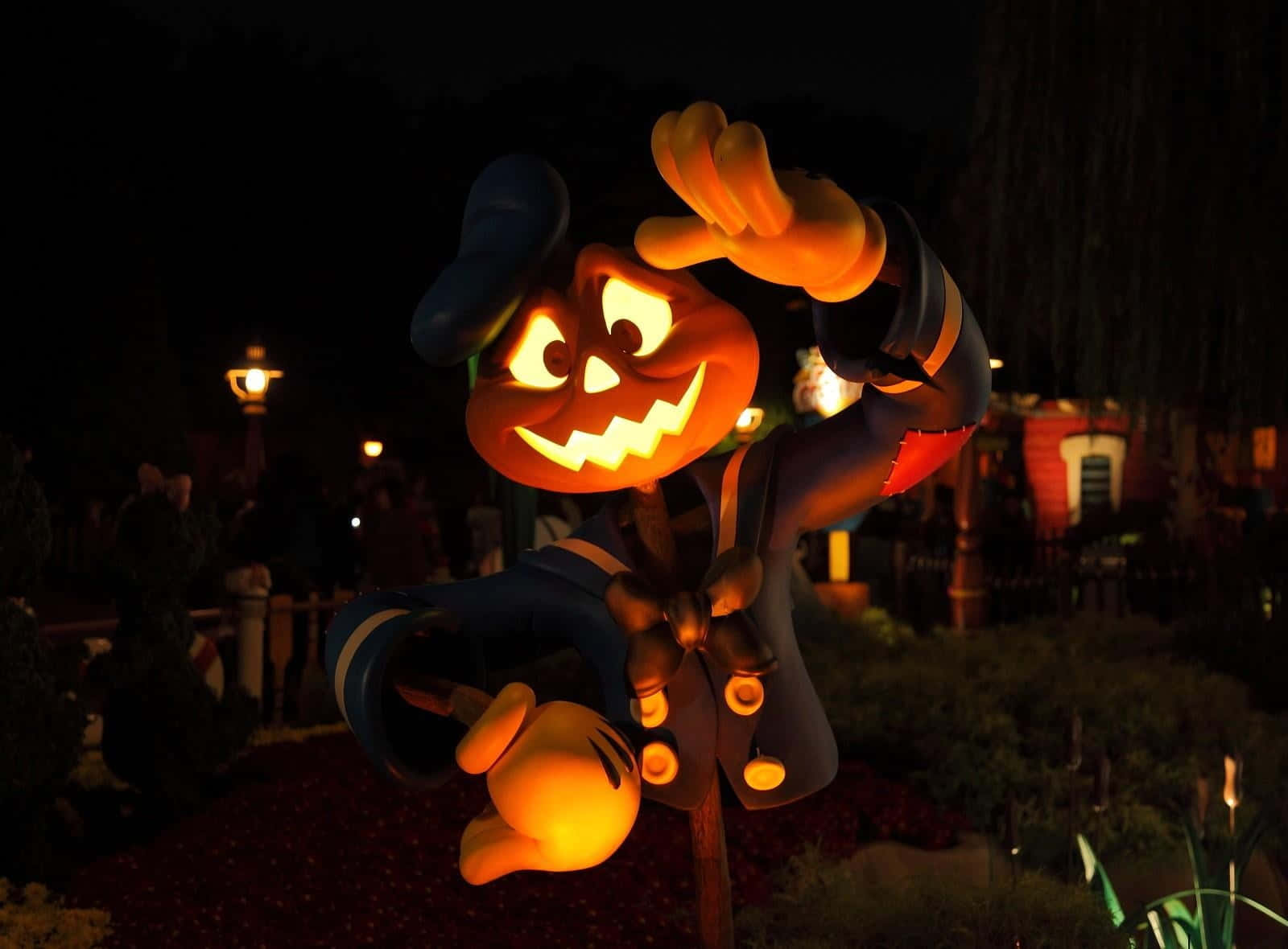 Jack O Lantern 桌布 壁紙 — 一個發光的傑克南瓜燈米奇老鼠雕像在萬聖節公園的夜晚愉快地揮手。