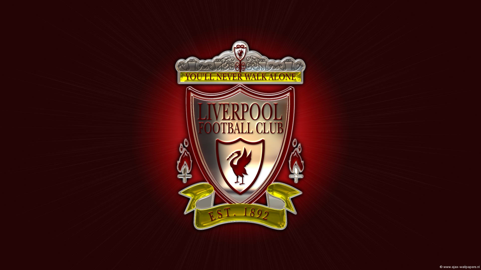Liverpool Fc 桌布 壁紙 — 一個發光的利物浦足球會徽章，帶有紅鳥和「You'll Never Walk Alone」格言，在深紅色背景上散發光芒。