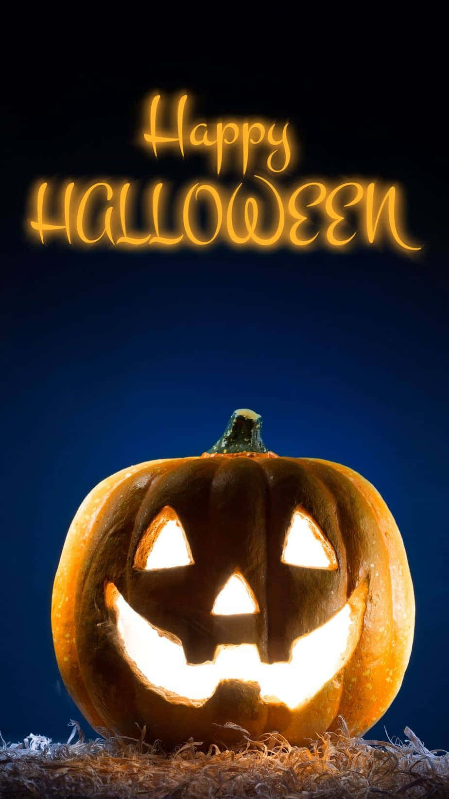 Jack O Lantern 桌布 壁紙 — 一個發光的南瓜帶著愉快的笑容坐在乾草上，背景是深藍色，上方有「Happy Halloween」文字。