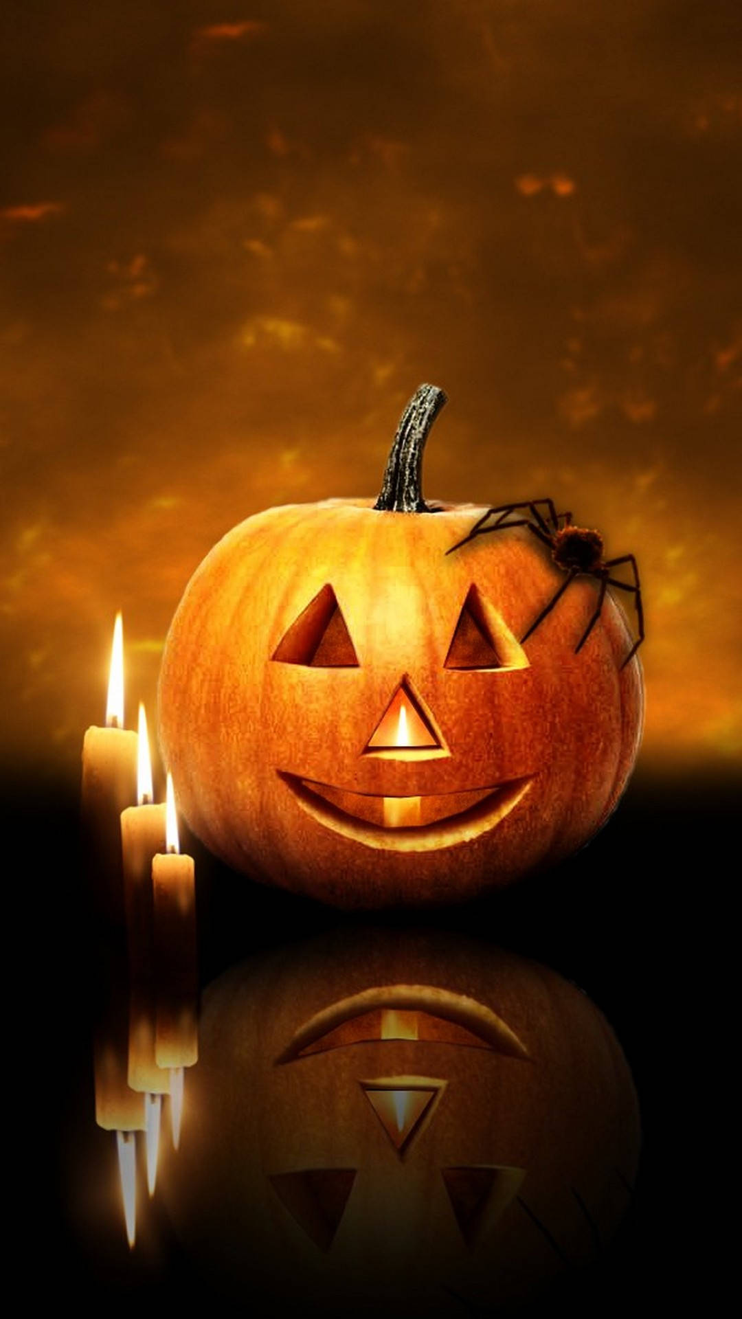 Halloween iPhone 桌布 壁紙 — 一個發光的南瓜燈，側面有一隻蜘蛛，兩旁點燃蠟燭，背景是溫暖的橙色。