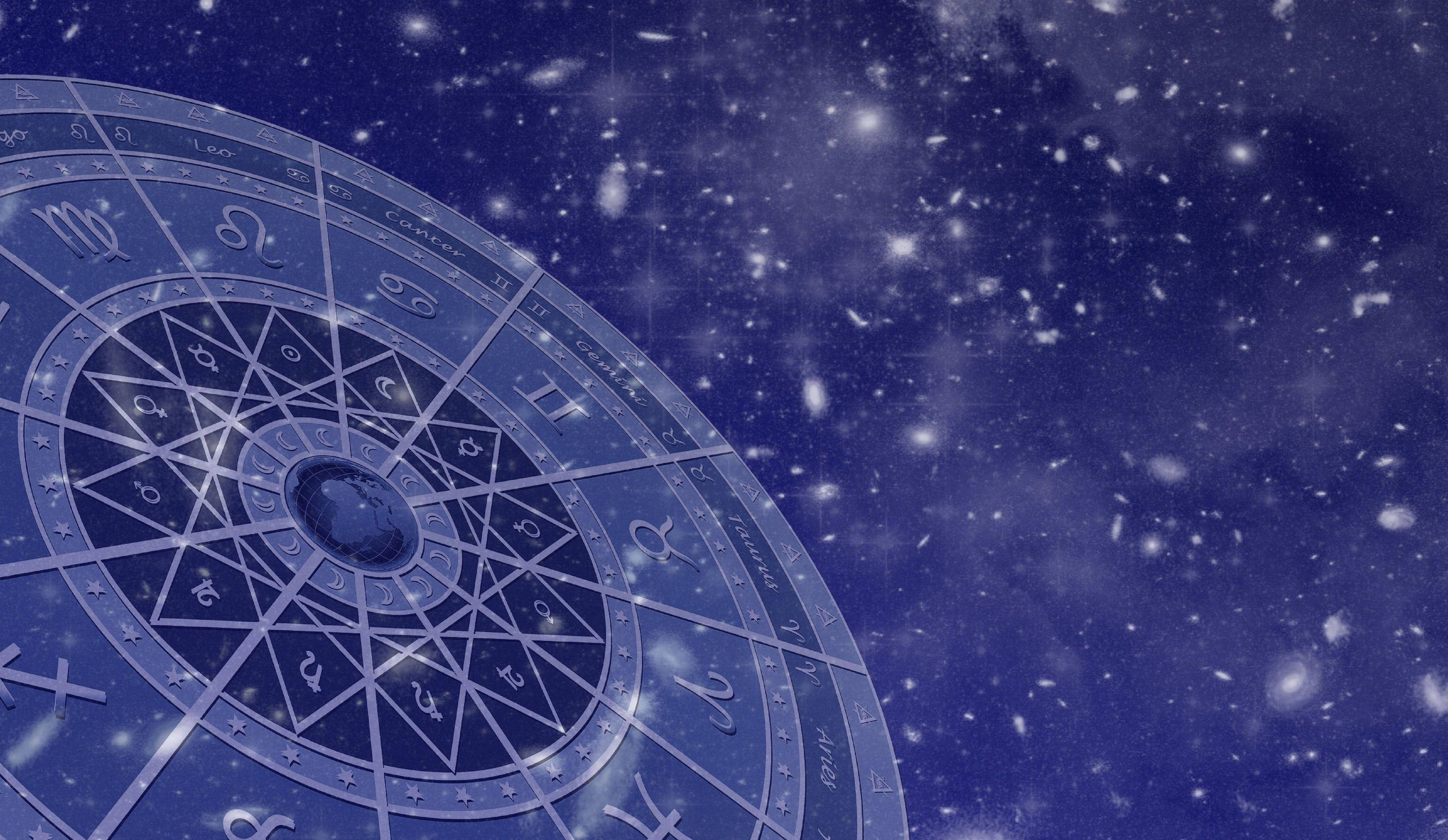 zodiac 桌布 壁紙 — 一個發光的占星輪盤，帶有星座符號，漂浮在星光閃爍的宇宙藍色背景上。
