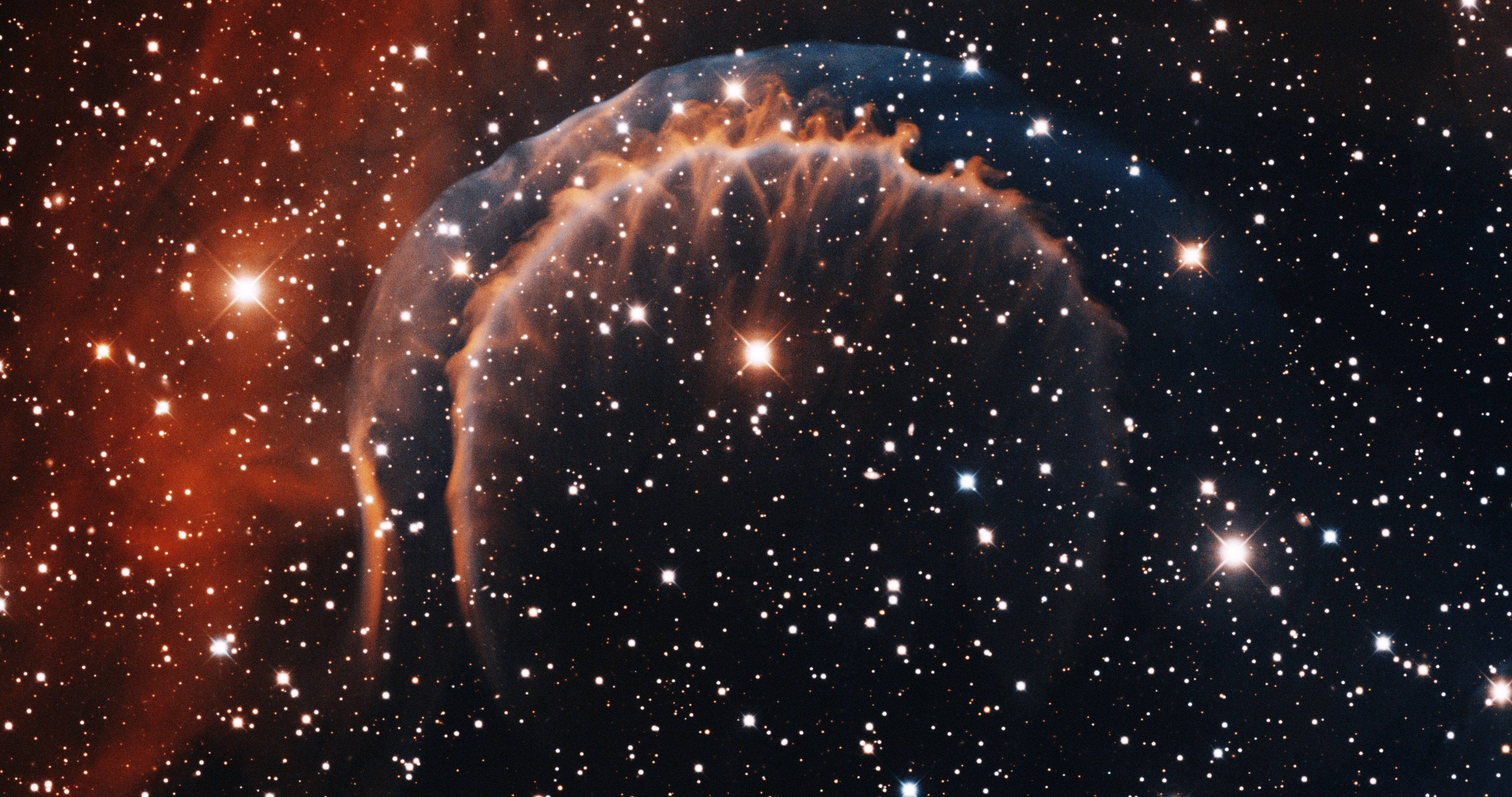 4K ultra HD galaxy 桌布 壁紙 — 一個發光的宇宙星雲，帶有火熱的橙色觸手和明亮的星星，背景是深邃的黑色太空。