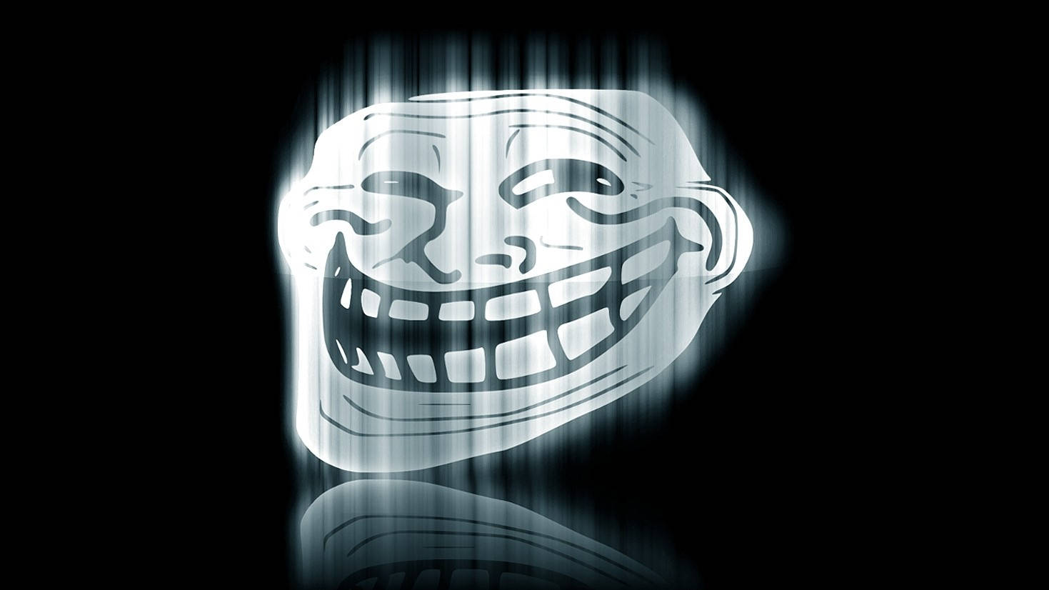 faces 桌布 壁紙 — 一個發光的巨魔臉孔，帶著寬闊的笑容和尖銳的牙齒，在黑色背景和下方的反射表面上散發光芒。