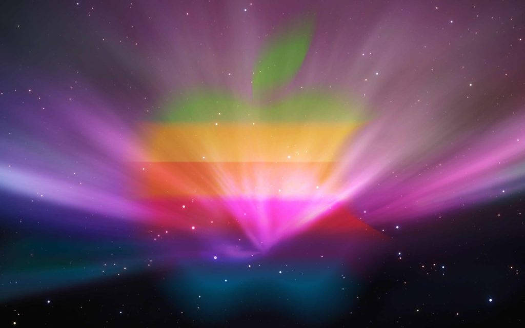 色彩 桌布 壁紙 — 一個發光的彩虹Apple標誌，在佈滿星星的宇宙天空中散發出彩色光束，背景有紫色和藍綠色的星雲。