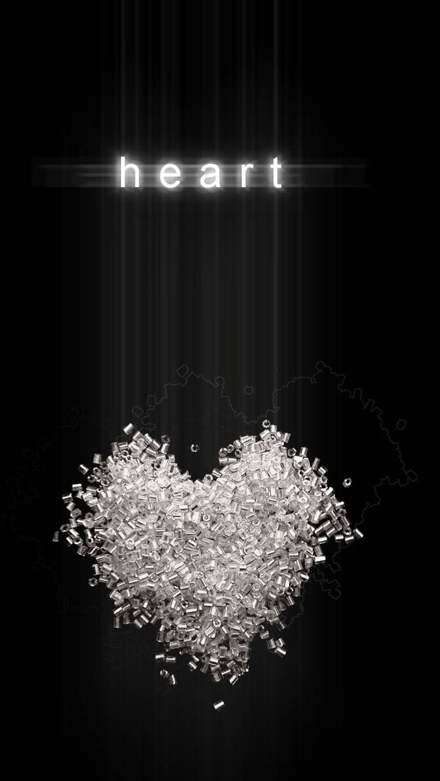 White Heart 桌布 壁紙 — 一個發光的愛心形狀，由散落的銀色塑膠顆粒在黑色背景上形成，帶有光線和上方的「心」字。