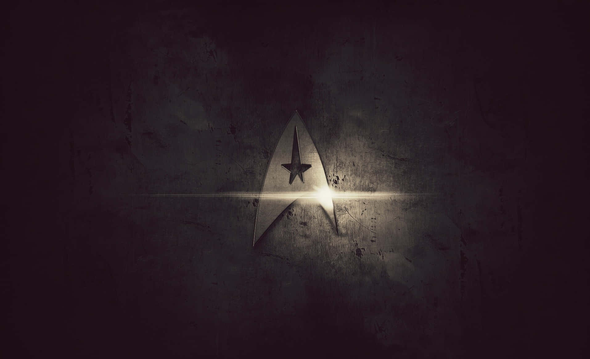 Logo 桌布 壁紙 — 一個發光的星際艦隊徽章在黑暗的紋理牆壁上閃耀，帶有戲劇性的燈光效果。
