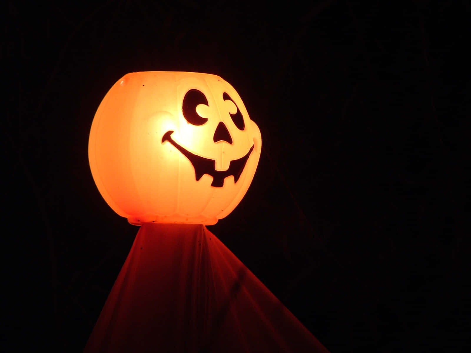 Pumpkin 桌布 壁紙 — 一個發光的橙色傑克南瓜燈，帶著微笑的臉，漂浮在黑暗的夜空中。