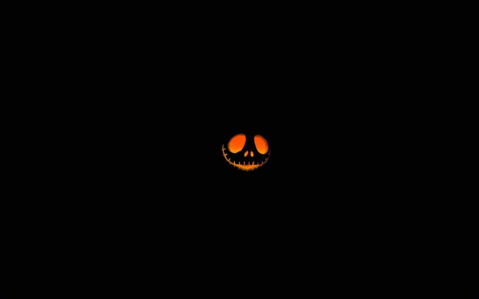 Dark Halloween 桌布 壁紙 — 一個發光的橙色傑克南瓜燈臉孔，帶有縫合的眼睛和笑容，獨自漂浮在漆黑的虛空中。