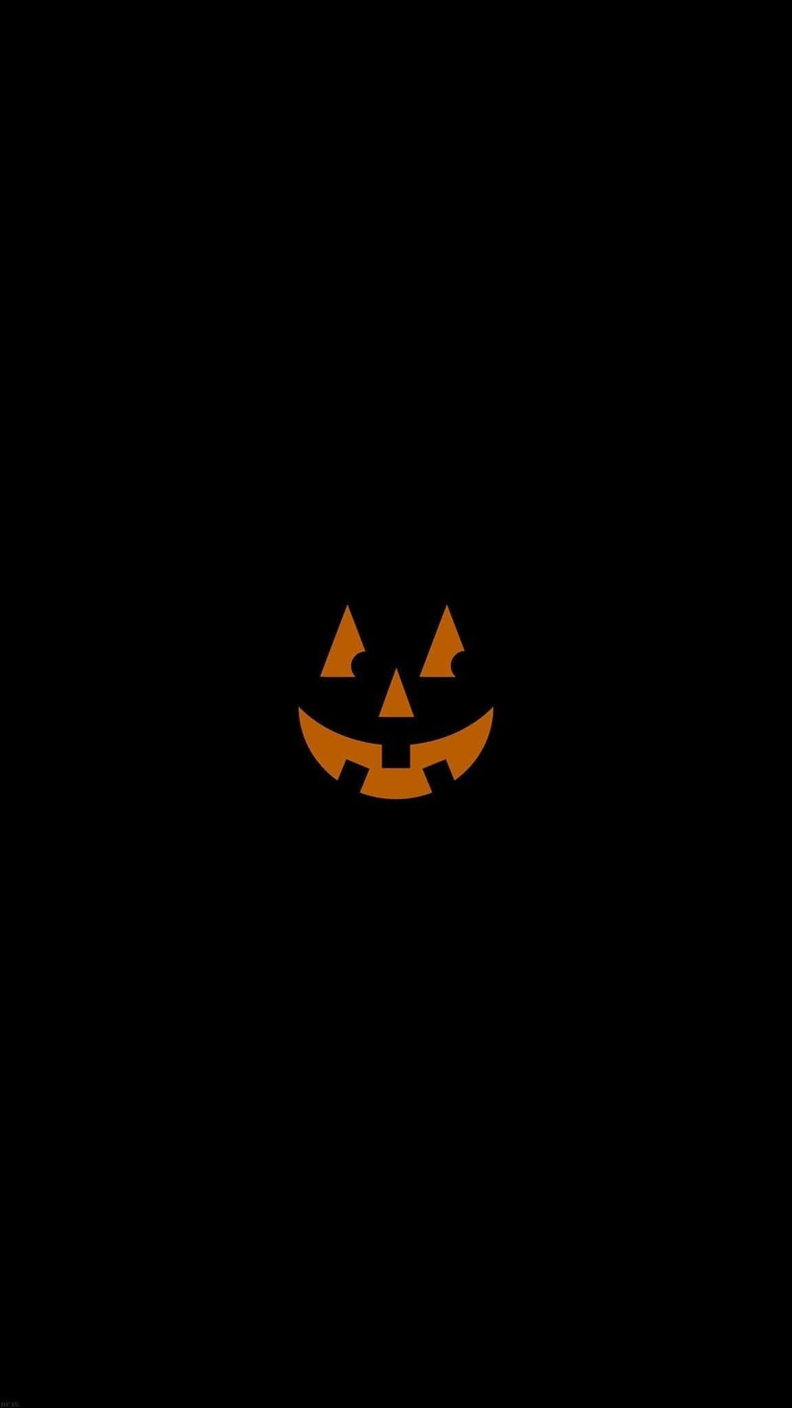 Halloween Laptop 桌布 壁紙 — 一個發光的橙色南瓜燈臉孔，帶有三角形眼睛和露齒笑容，居中在純黑色背景上。