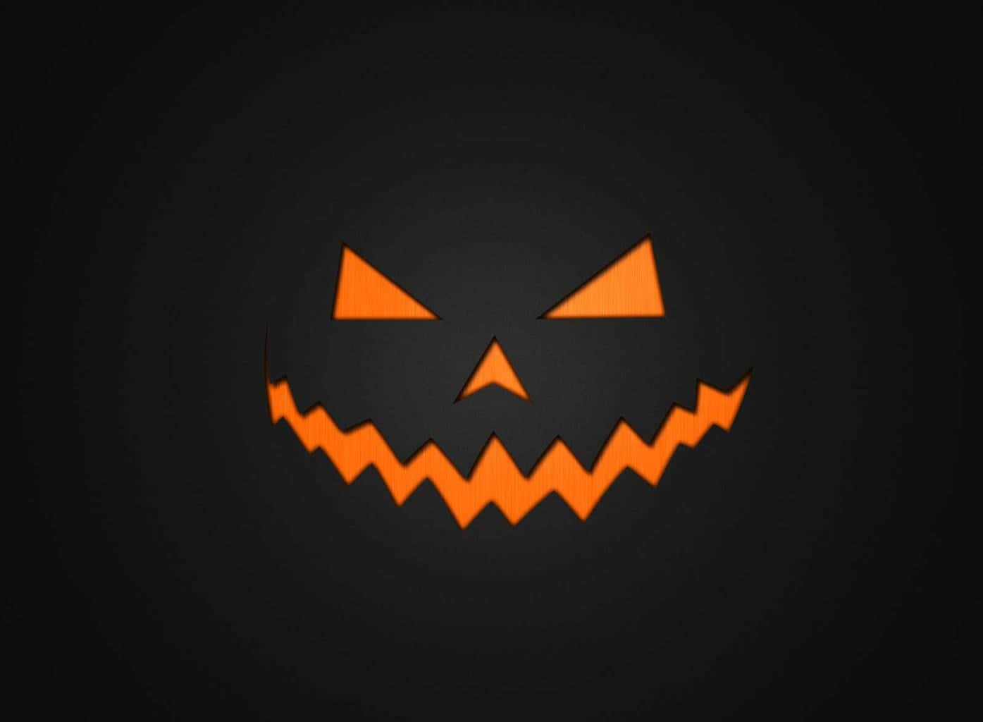 Aesthetic Creepy Halloween 桌布 壁紙 — 一個發光的橙色南瓜燈臉孔，帶有三角形眼睛和鋸齒狀的笑容，在深色背景上。