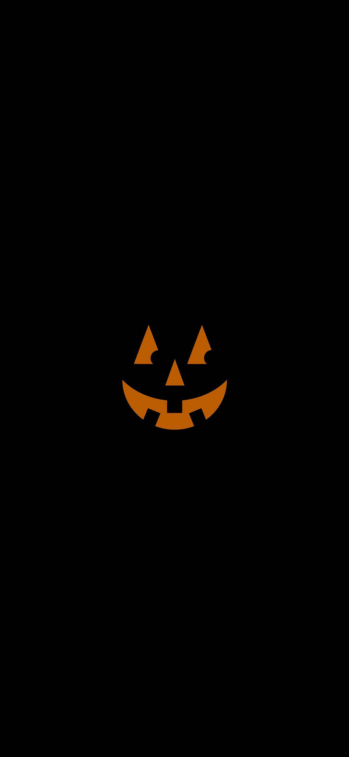 Halloween iPhone 桌布 壁紙 — 一個發光的橙色南瓜燈臉孔，帶有三角形眼睛和鋸齒狀笑容，居中在純黑色背景上。