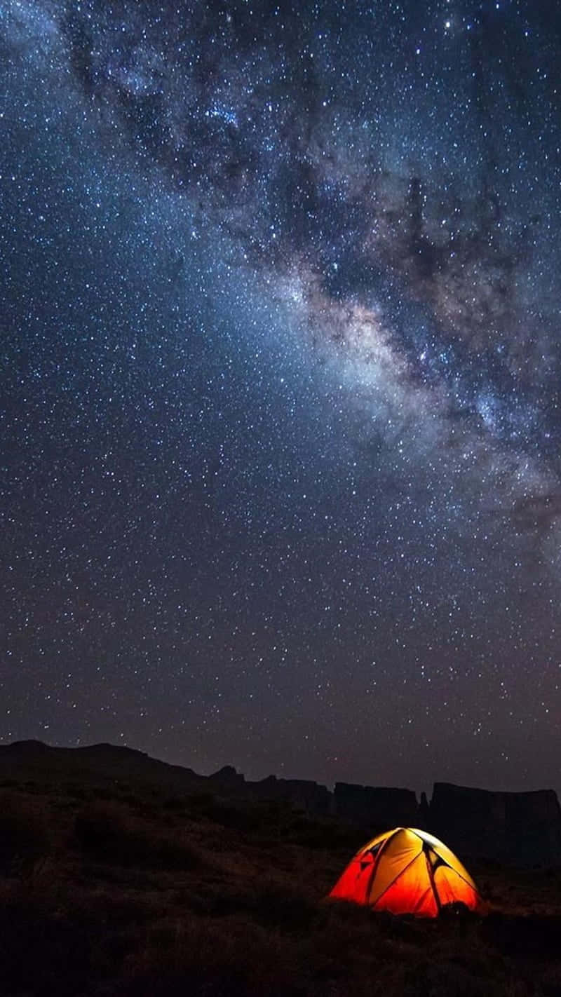 Light 桌布 壁紙 — 一個發光的橙色帳篷獨自矗立在令人嘆為觀止的星空下，銀河拱橋在上方。
