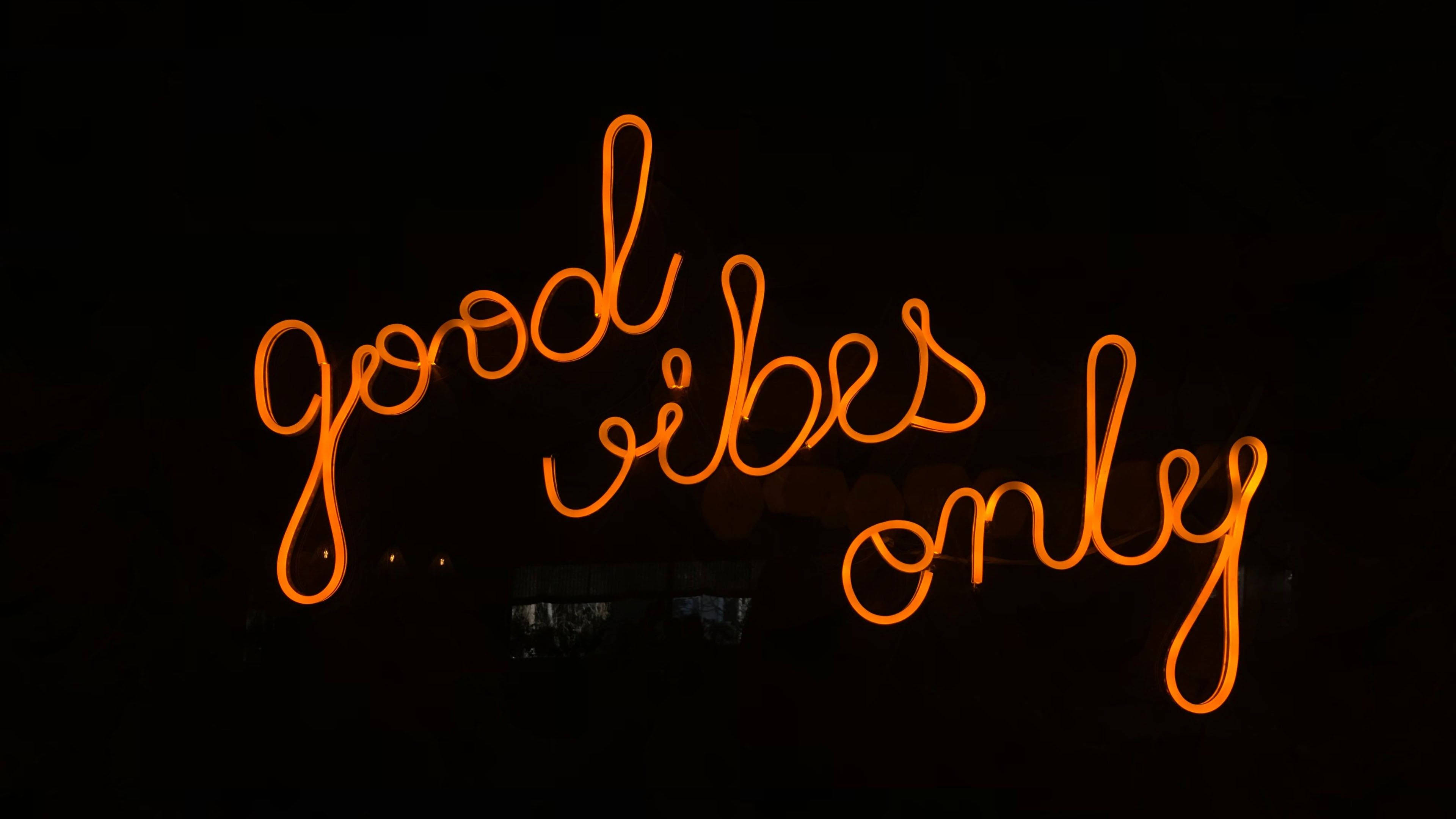 氛圍 桌布 壁紙 — 一個發光的橙色霓虹燈牌在黑暗背景上顯示 good vibes only。