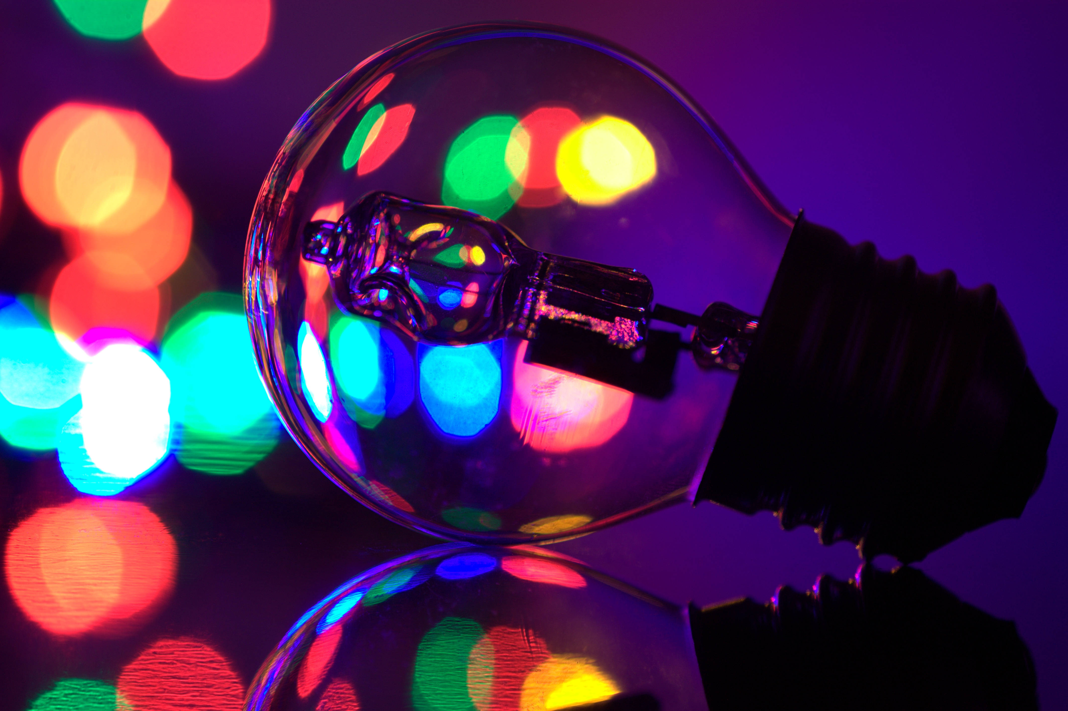Bokeh 桌布 壁紙 — 一個發光的燈泡在深紫色背景上反射出鮮豔的散景光。