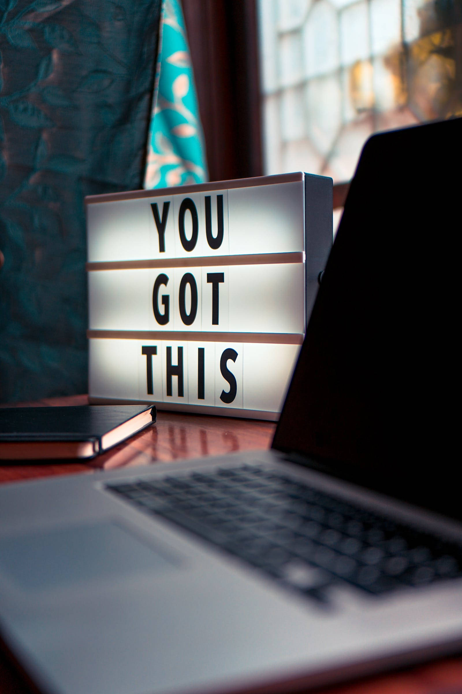 Motivational Quotes 桌布 壁紙 — 一個發光的燈箱，上面寫著「YOU GOT THIS」，放在窗邊木桌的筆記型電腦旁。
