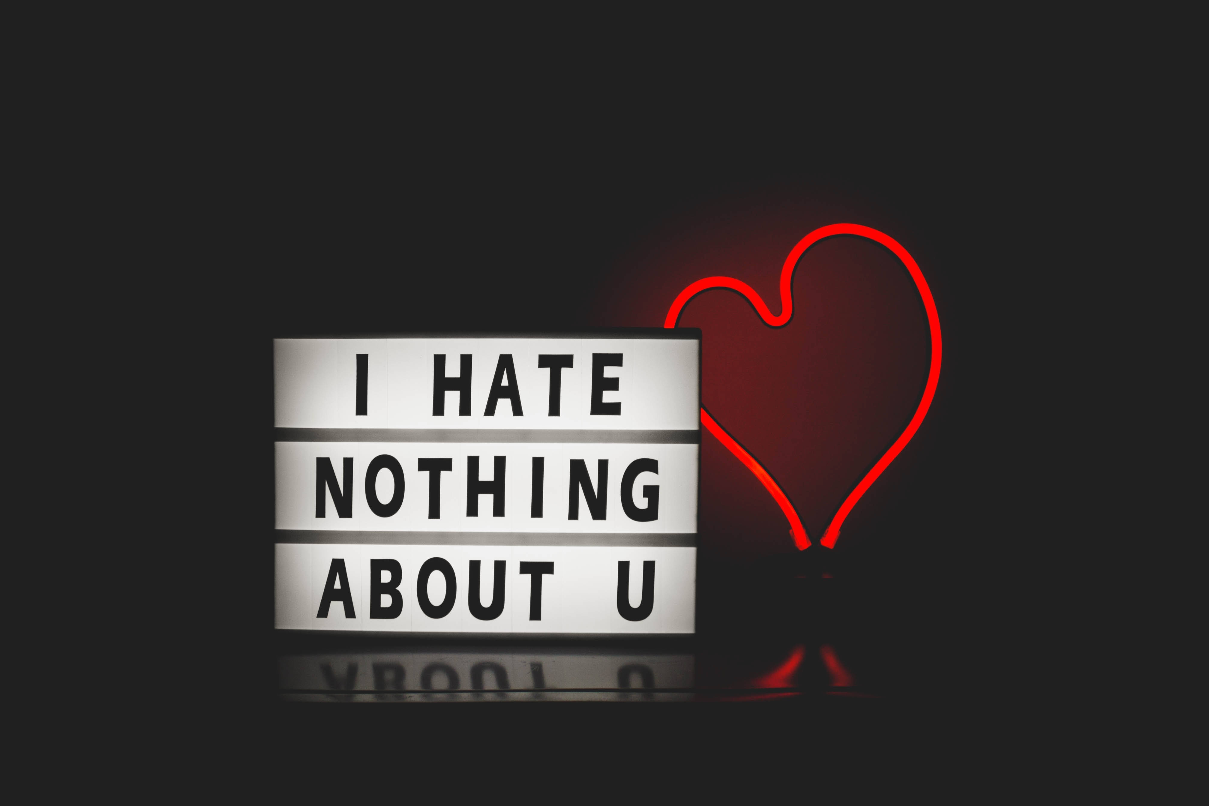 愛心 桌布 壁紙 — 一個發光的燈箱在黑暗背景上顯示「I HATE NOTHING ABOUT U」字句，旁邊有一個紅色霓虹心形。