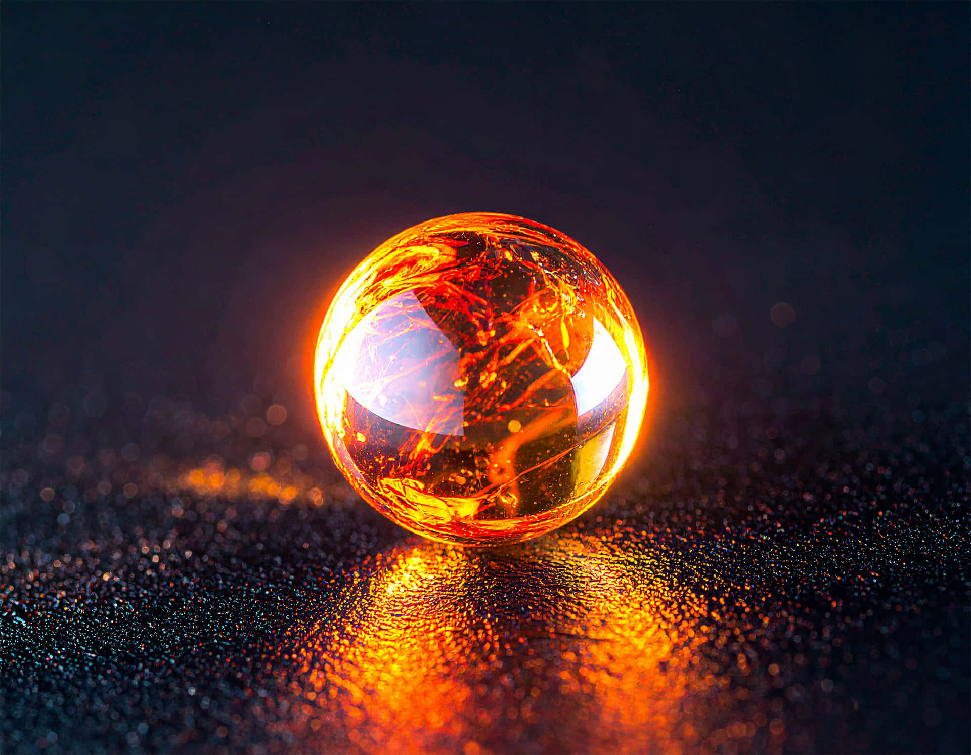 Molten Droplet 壁紙 — 一個發光的琥珀色玻璃球放置在深色閃爍的表面上，在深黑色背景上投射出溫暖的橙色反射。