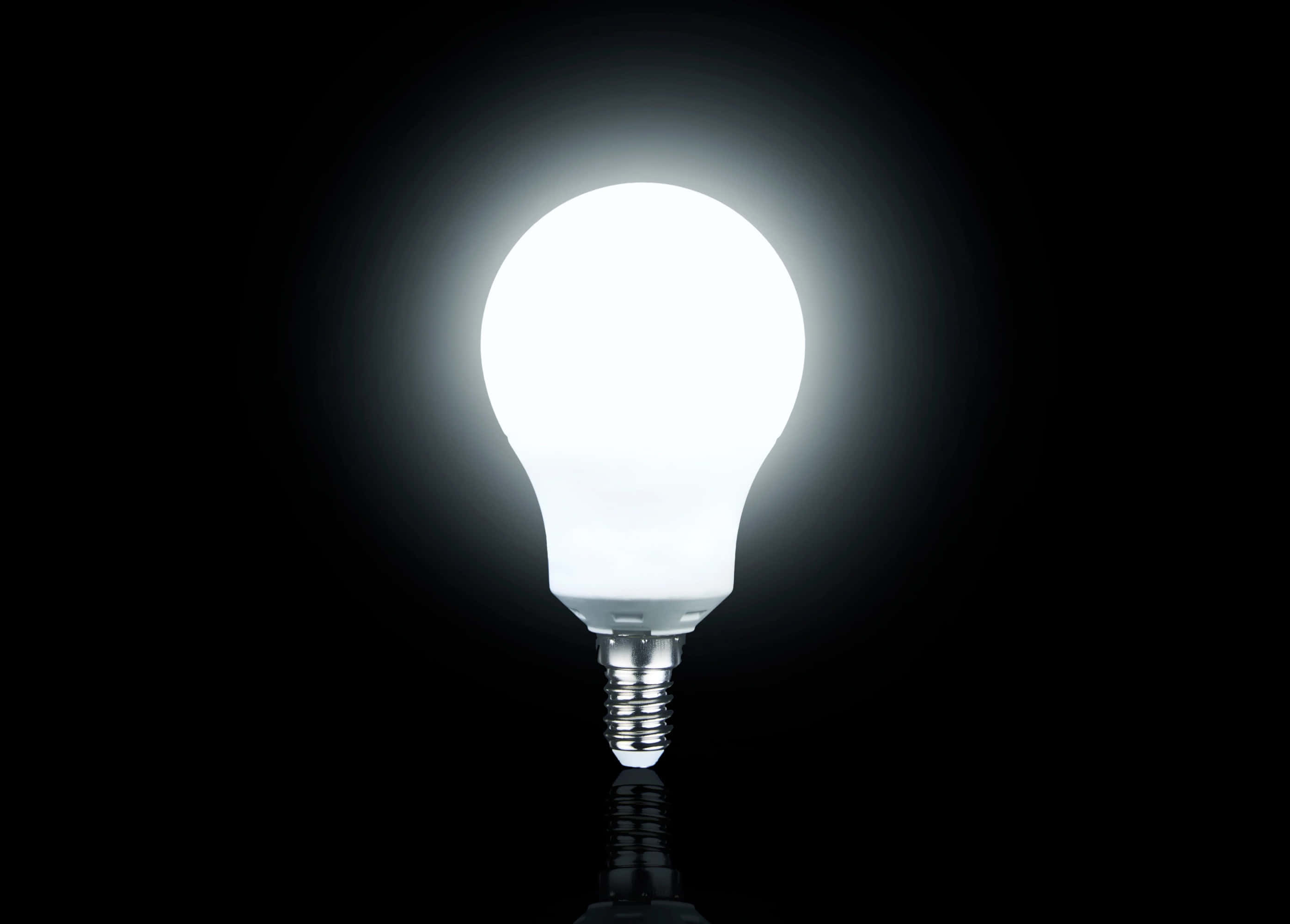 Light 桌布 壁紙 — 一個發光的白色LED燈泡在純黑色背景上明亮地發光，下方有微妙的反射。