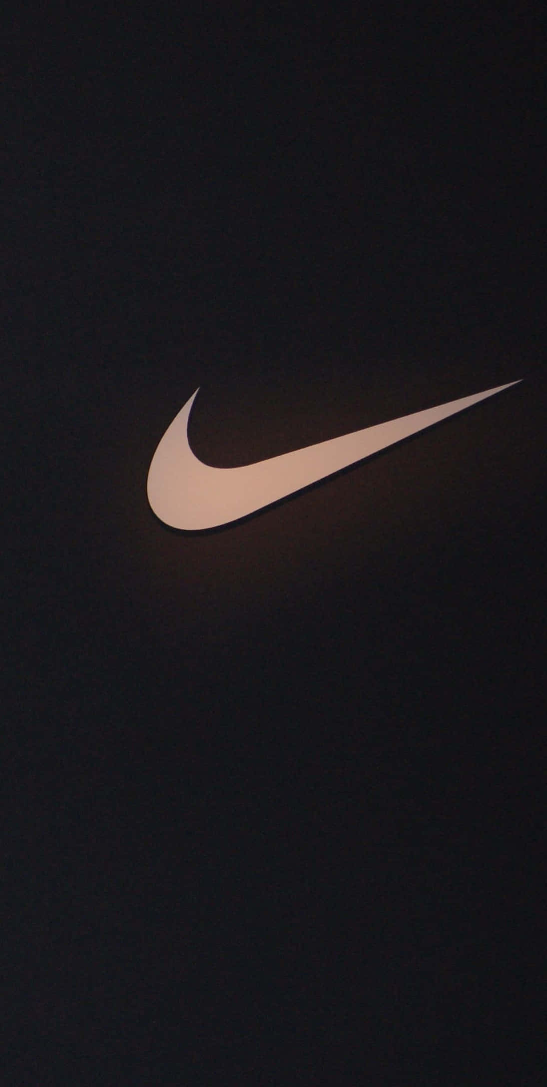 Nike Logo 桌布 壁紙 — 一個發光的白色Nike Swoosh標誌，居中於深色紋理背景上，帶有柔和環境光。