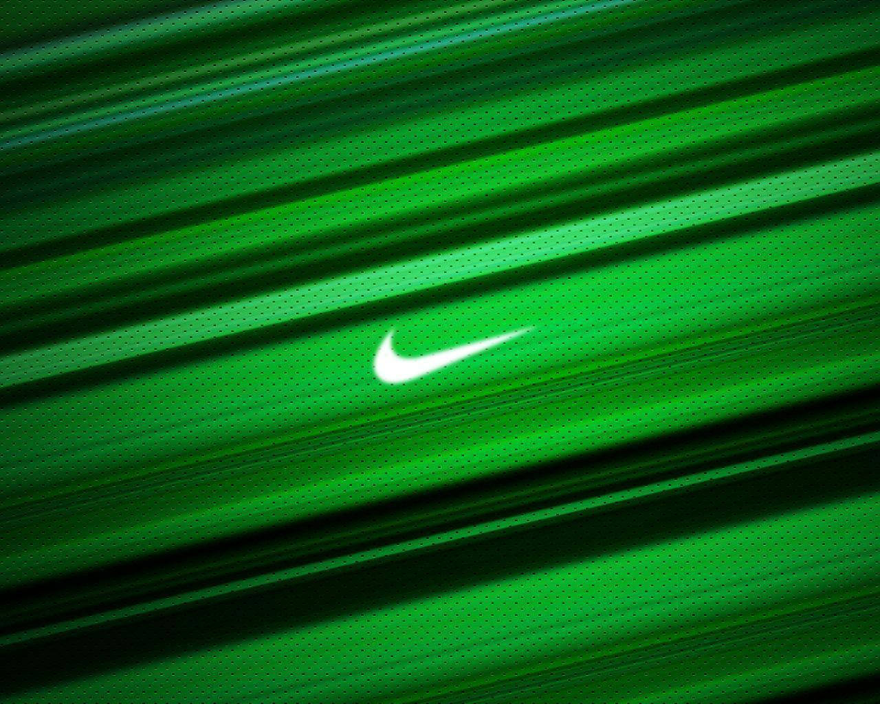 酷炫耐吉 桌布 壁紙 — 一個發光的白色Nike勾勾標誌，居中於充滿活力的綠色紋理布料上，帶有對角線動態模糊條紋。