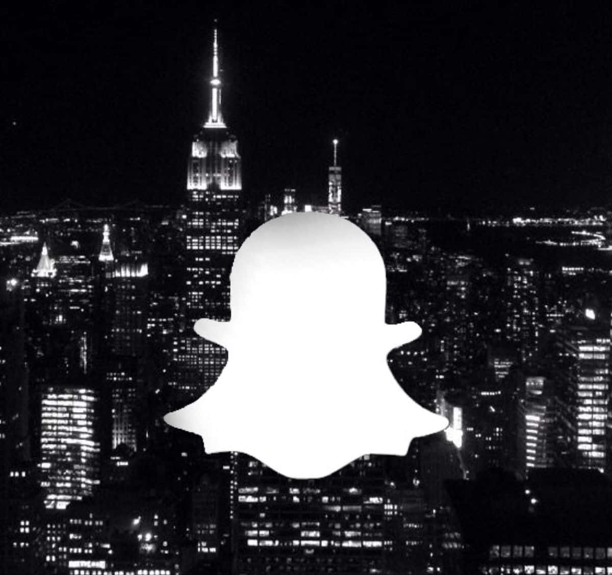snap 桌布 壁紙 — 一個發光的白色Snapchat鬼魂標誌疊加在包含帝國大廈的黑白夜間城市景觀上。