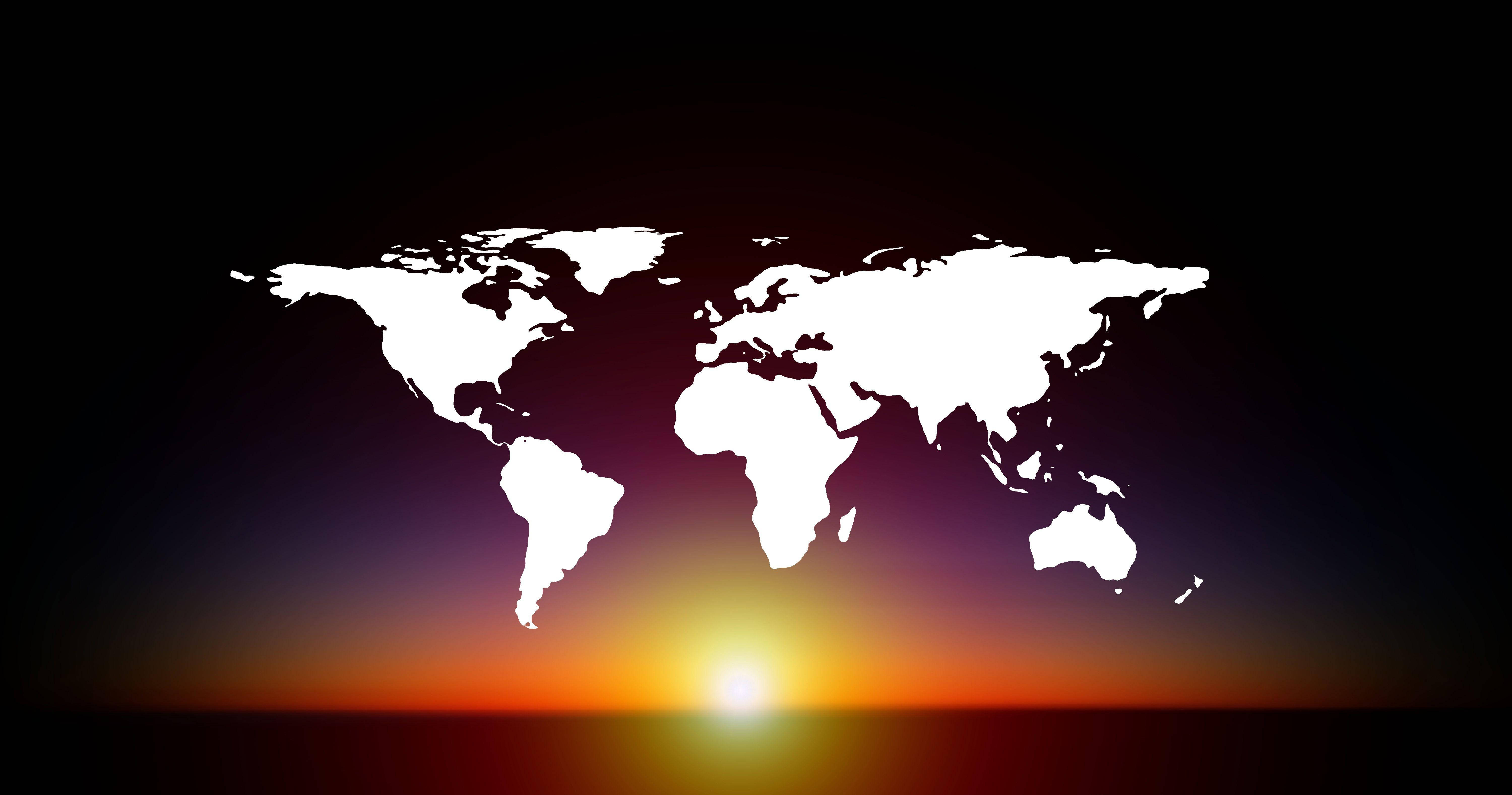 World Map Desktop 桌布 壁紙 — 一個發光的白色世界地圖剪影，映襯著充滿活力的日落漸變天空。