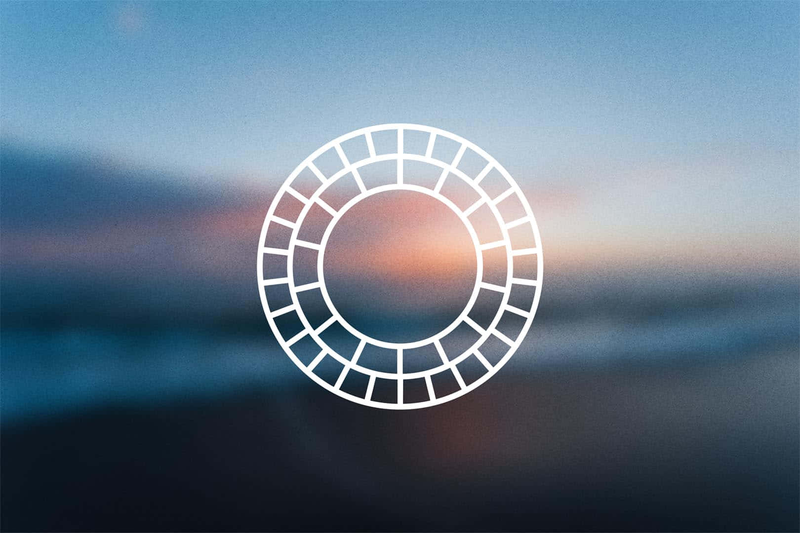 vsco 桌布 壁紙 — 一個發光的白色幾何圓形，帶有分段環，疊加在從藍色過渡到溫暖橙色的柔和漸變天空上。