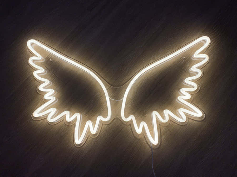 Neon Lights Aesthetic 桌布 壁紙 — 一個發光的白色霓虹天使翅膀標誌安裝在深色木牆上，投射出柔和的光線。