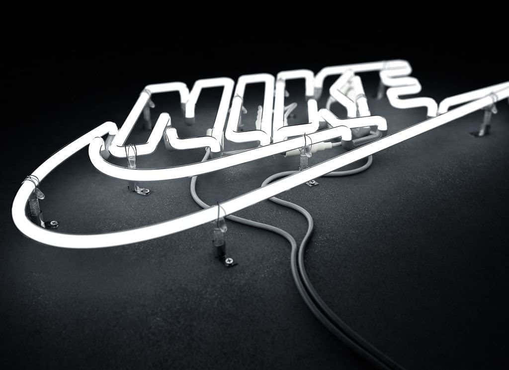 Nike Logo 桌布 壁紙 — 一個發光的白色霓虹燈Nike勾和標誌，放置在帶有可見線路的深色紋理表面上。