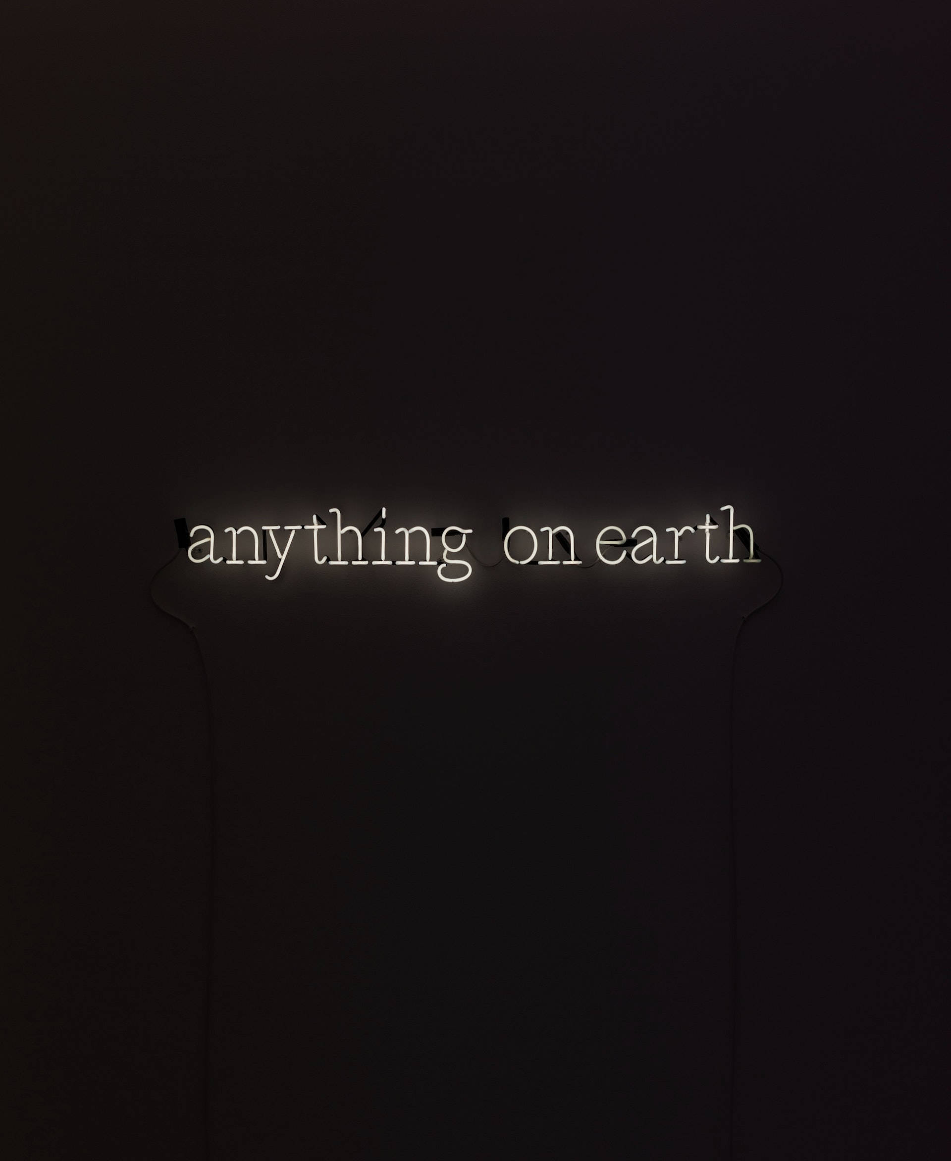 Black Phone 桌布 壁紙 — 一個發光的白色霓虹燈牌，上面寫著 anything on earth，掛在深色牆上，投射出柔和的光線。