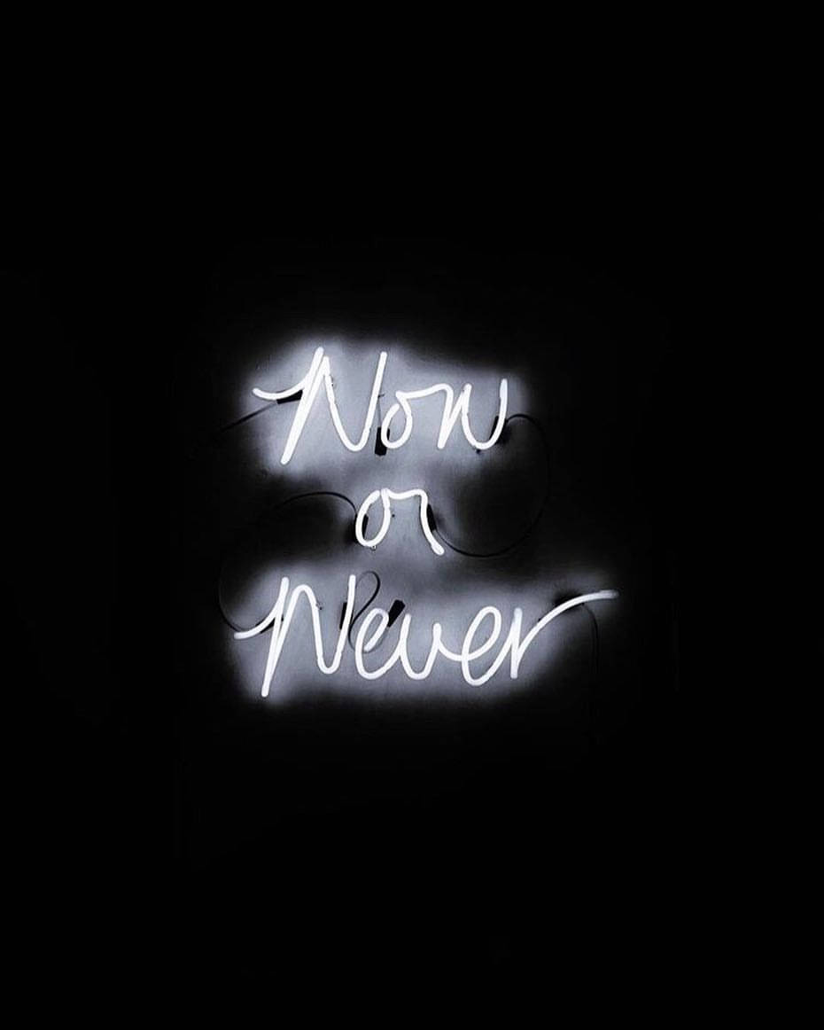trust 桌布 壁紙 — 一個發光的白色霓虹燈牌，上面寫著「Now or Never」，在漆黑的背景上投射出柔和的光芒。