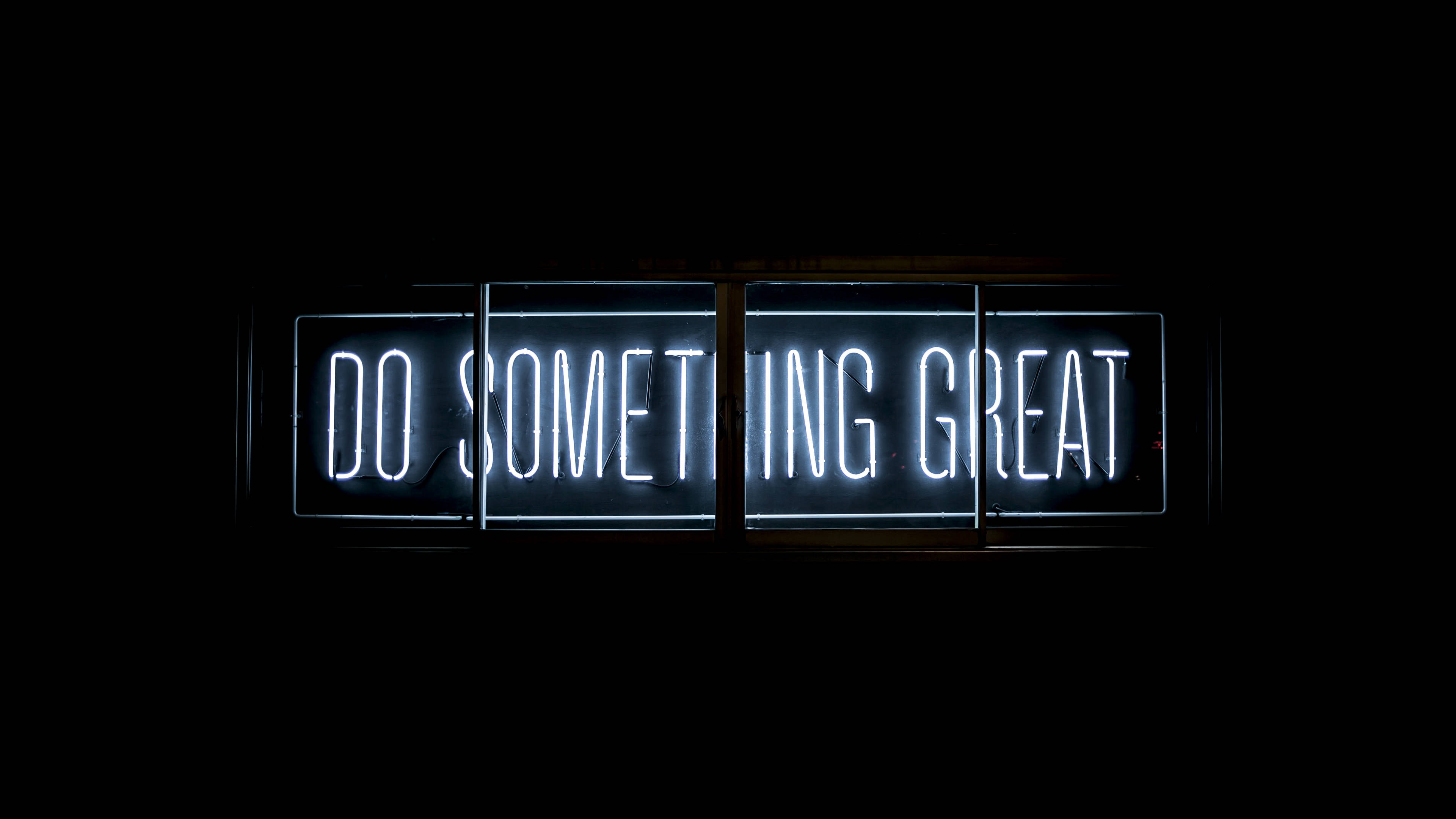 鎖屏 桌布 壁紙 — 一個發光的白色霓虹燈牌，上面用粗體字寫著「DO SOMETHING GREAT」，背景是漆黑的。