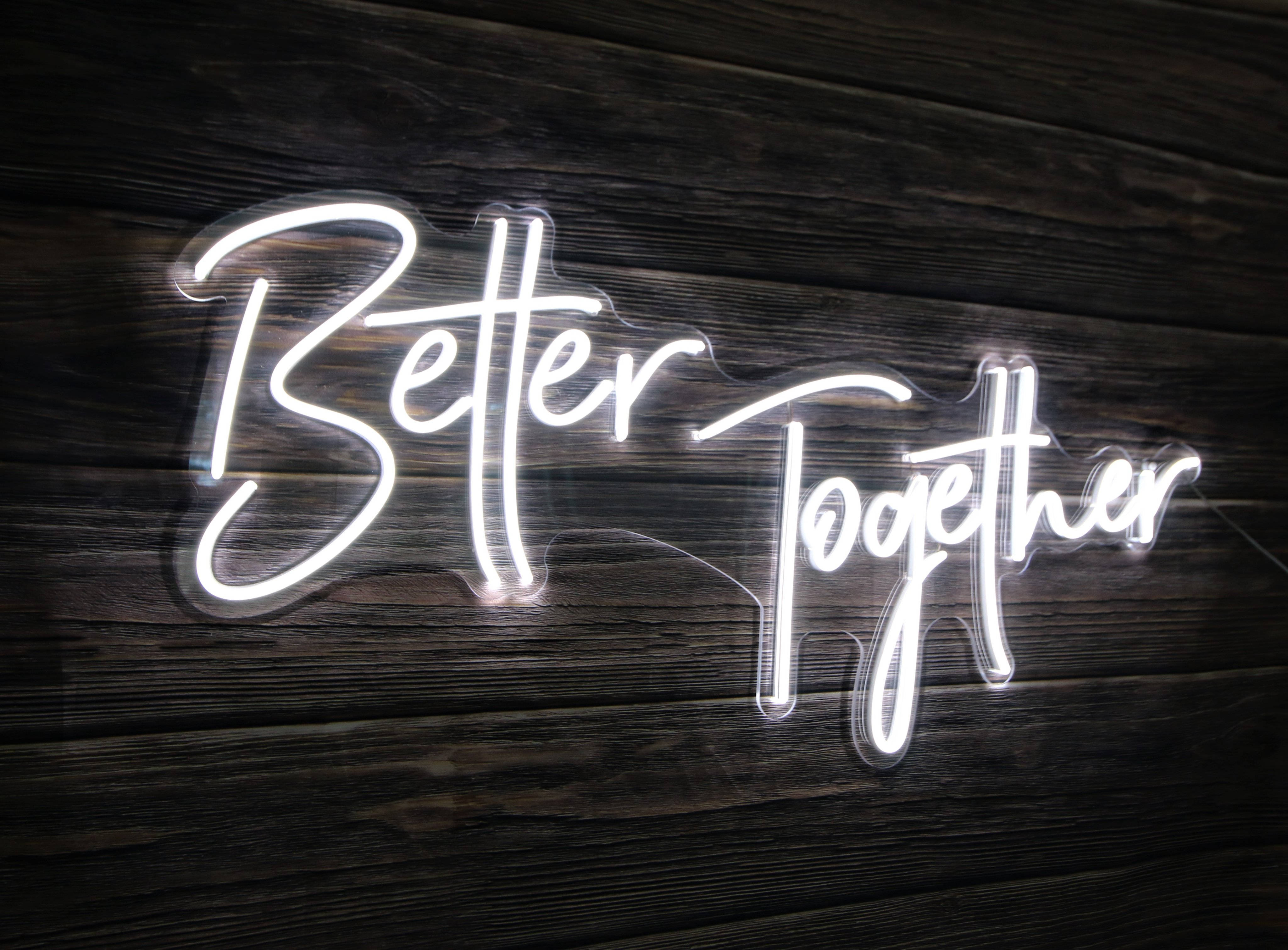 黑白 桌布 壁紙 — 一個發光的白色霓虹燈牌，以草書寫著「Better Together」，安裝在深色木板上。